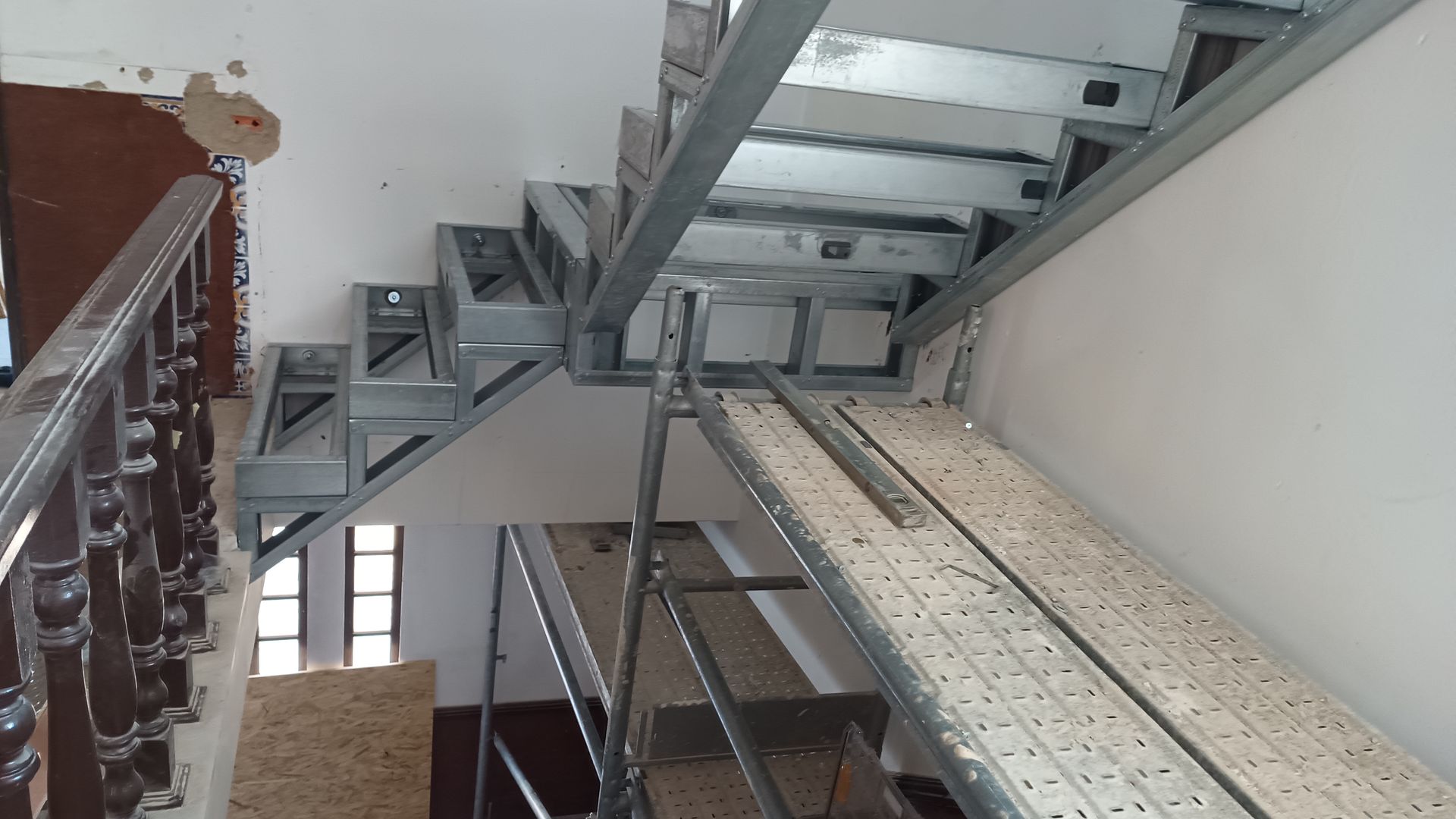 Estrutura metálica de escada em construção, com degraus de madeira.
