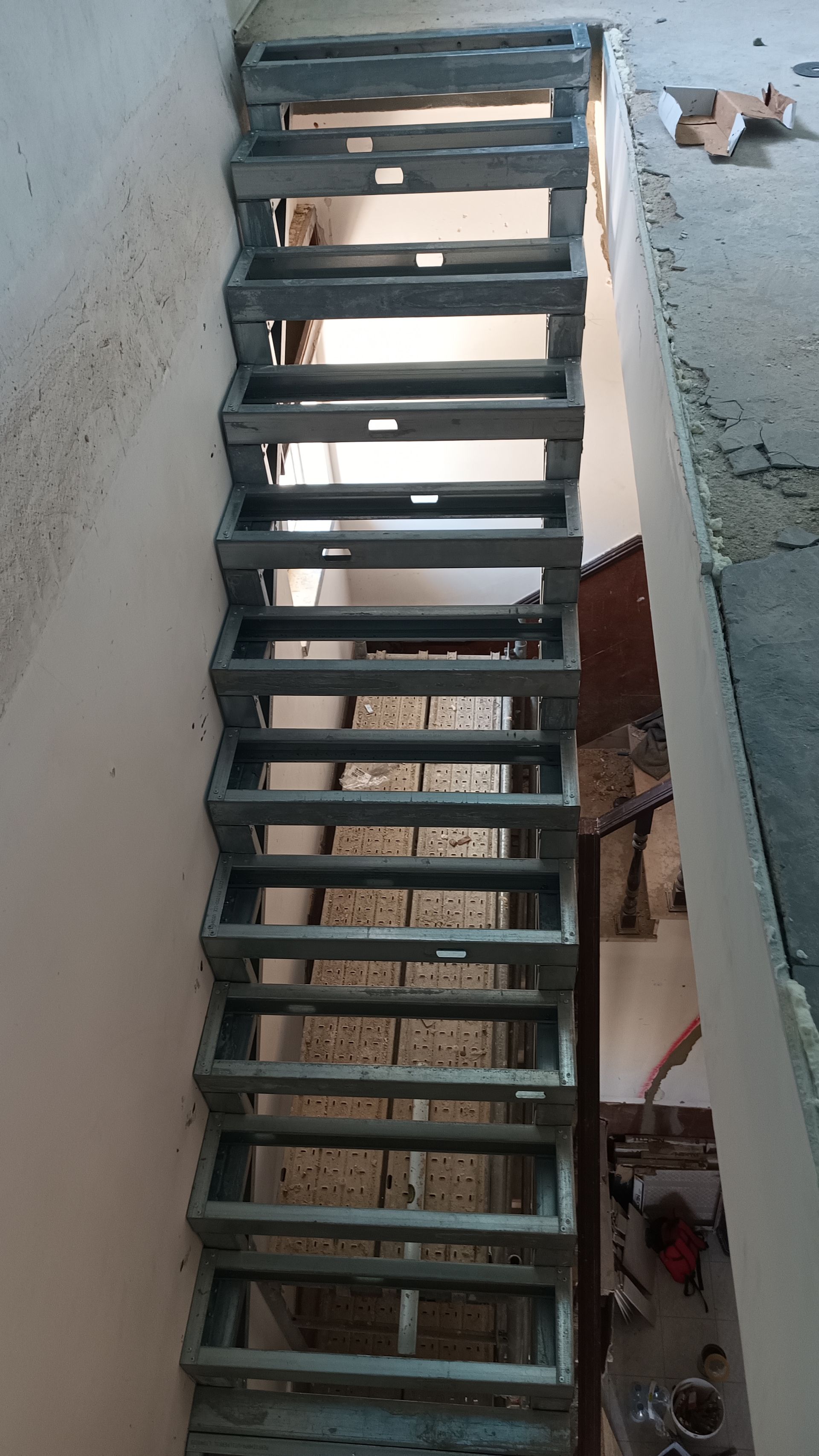 Estrutura metálica de escada, possivelmente em construção, dentro de um edifício.