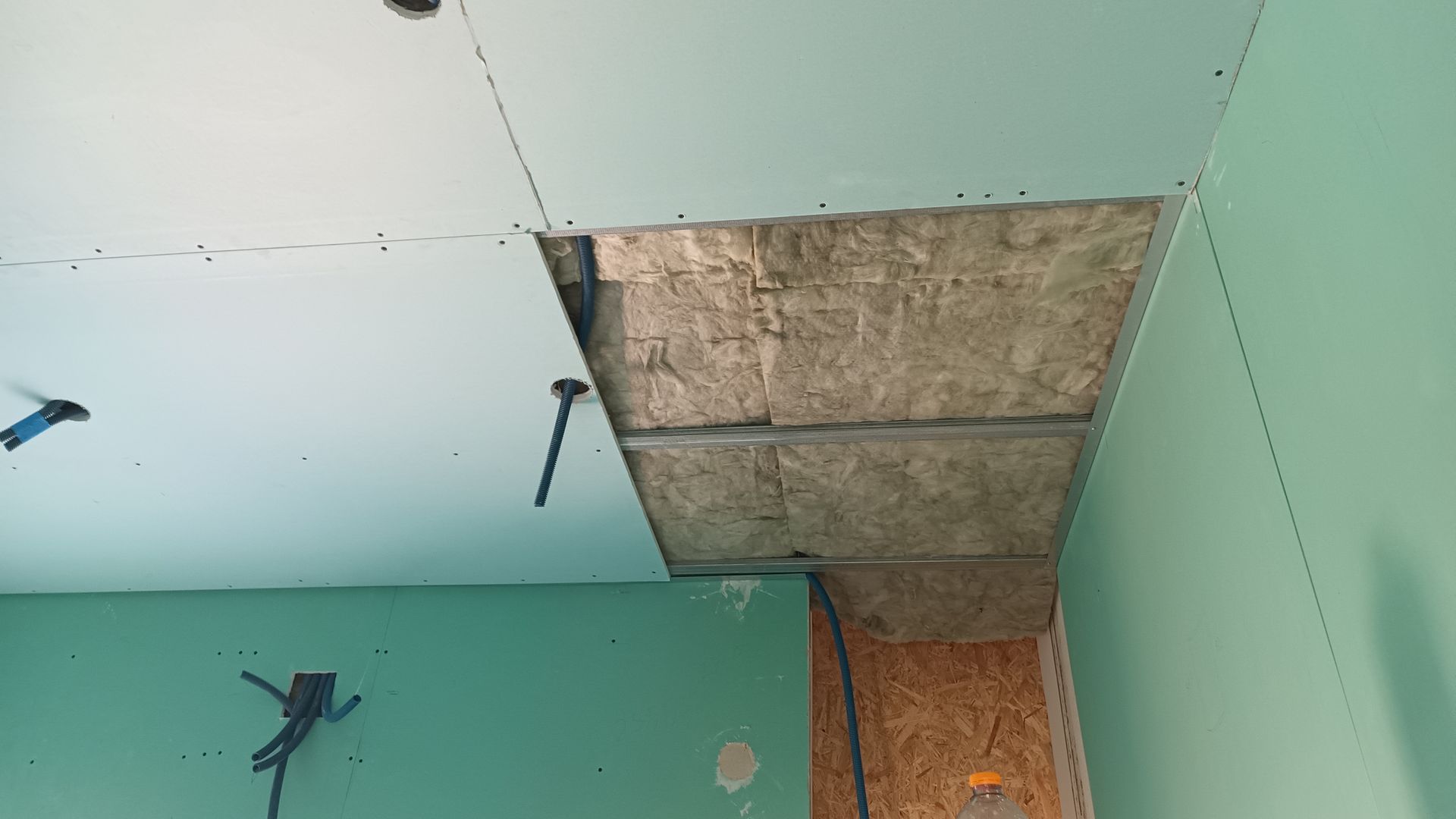 Teto em construção, com isolamento aparente e drywall verde. Vista interna.