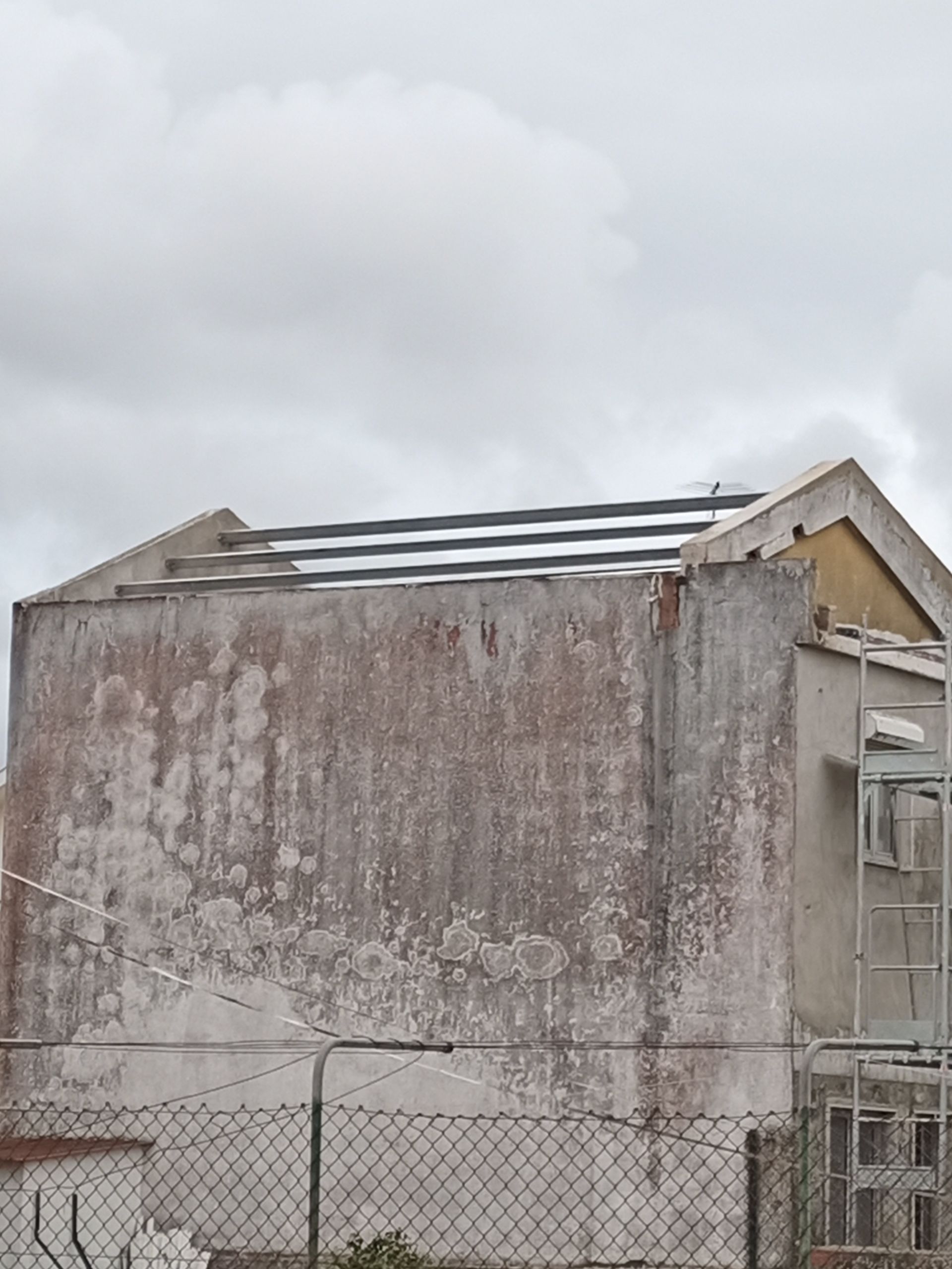 Prédio deteriorado com o telhado parcialmente removido sob um céu nublado.