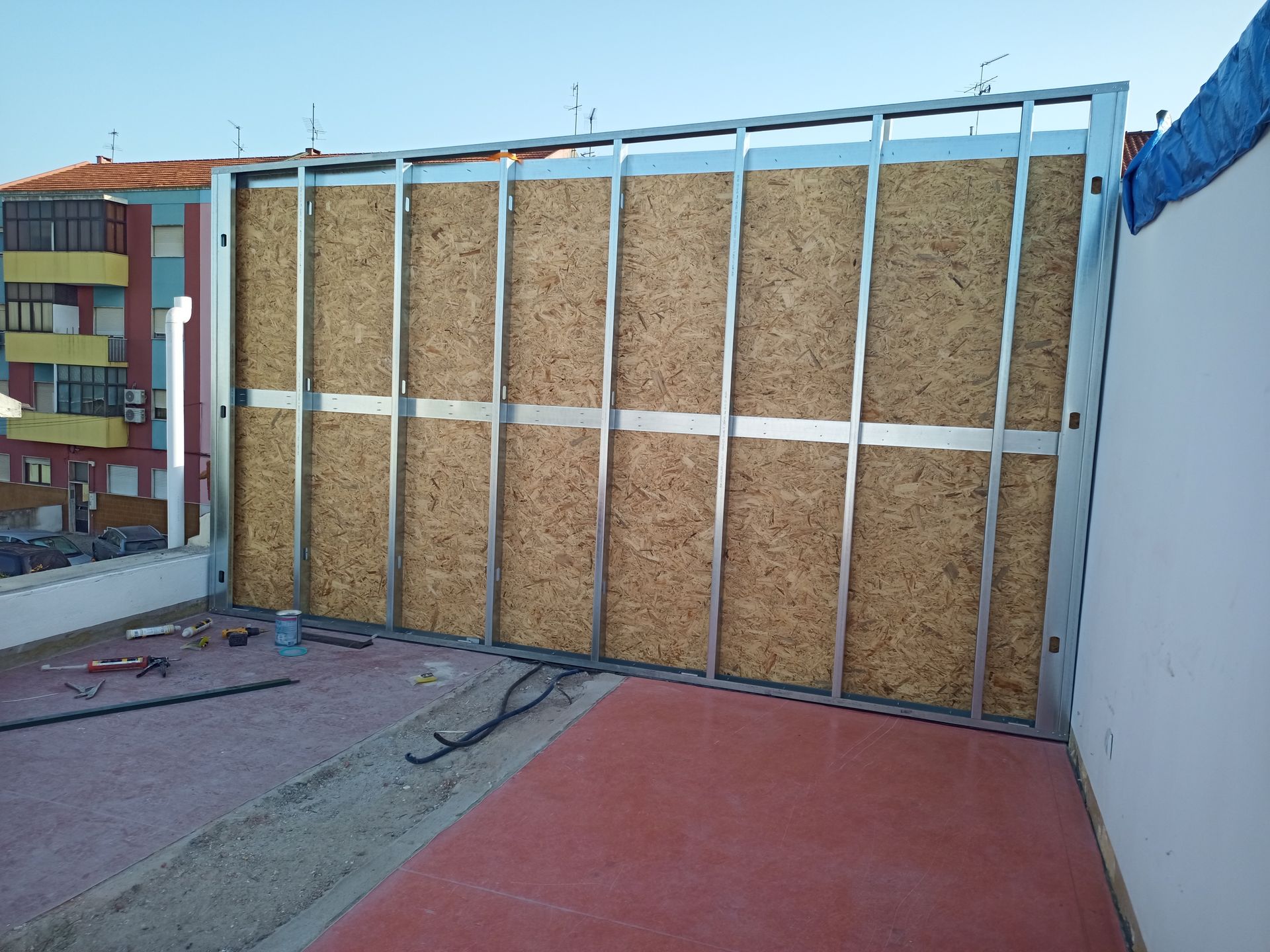 Estrutura metálica e painéis de madeira sendo montados em um telhado.