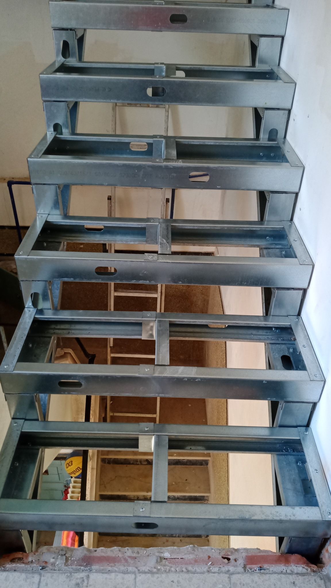 Estrutura metálica da escada já montada, pronta para receber os degraus. Ambiente interno.