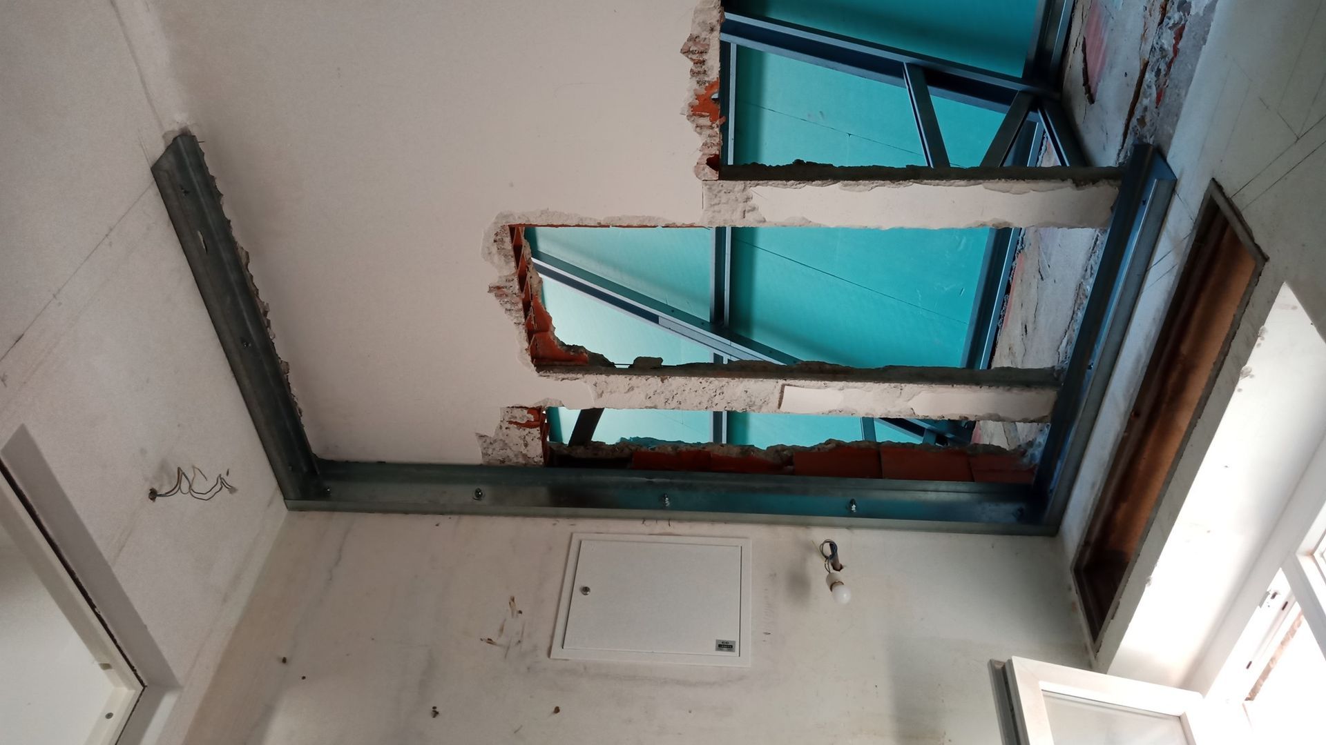 Teto com aberturas retangulares, revelando vigas metálicas e tijolos aparentes.