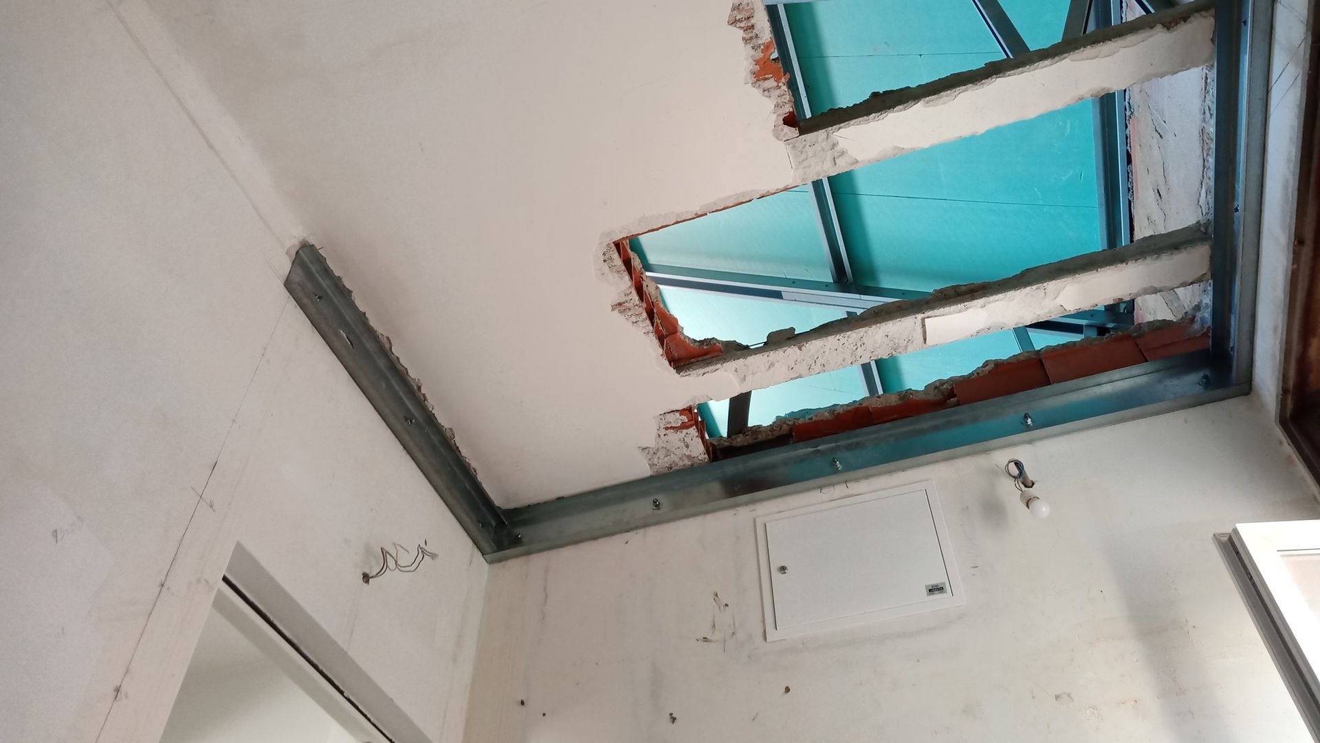 Teto com buraco, vigas metálicas expostas; danos e necessidade de reparo.