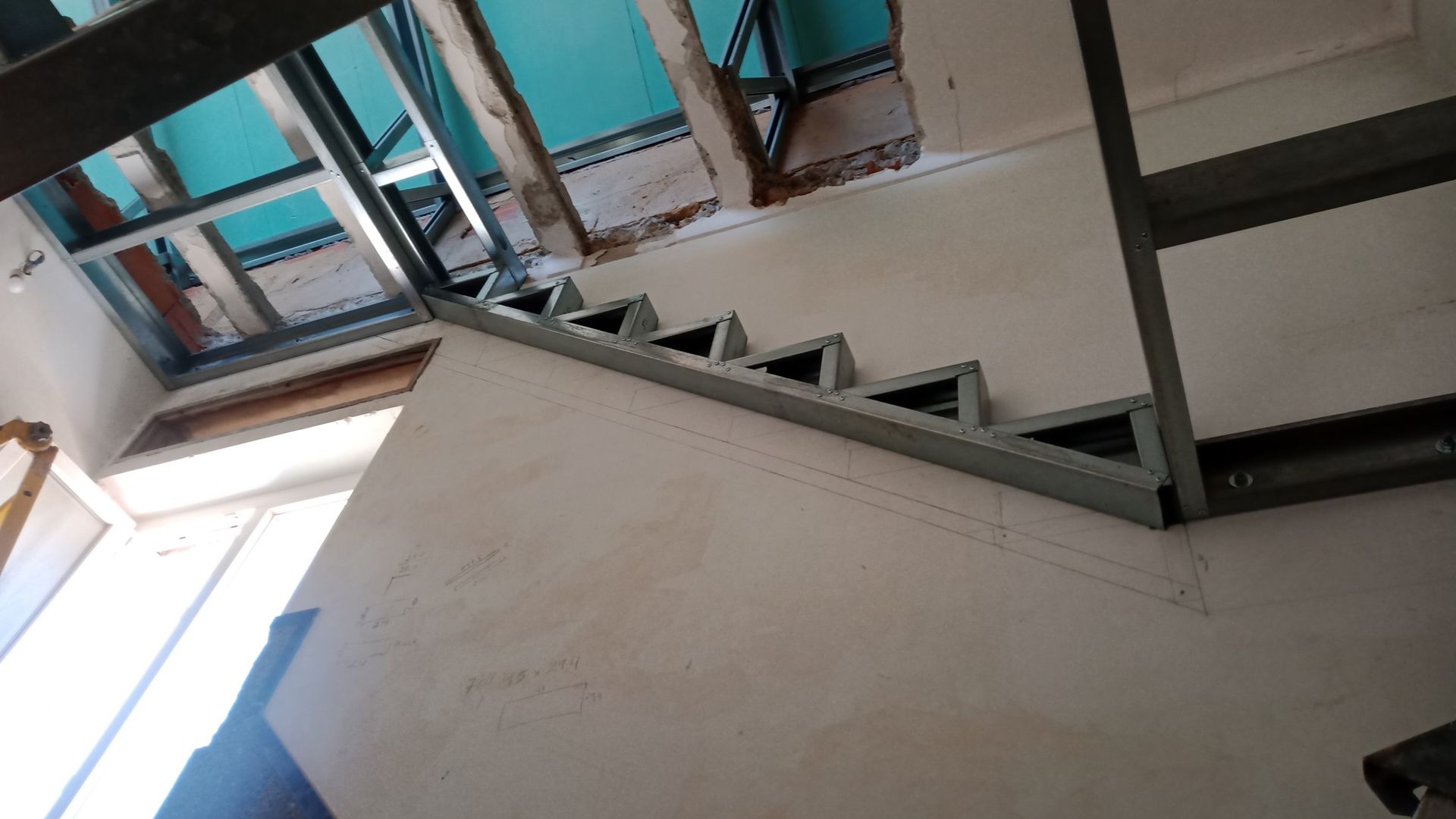 Escada com estrutura metálica em construção, com degraus e estrutura do teto visíveis.