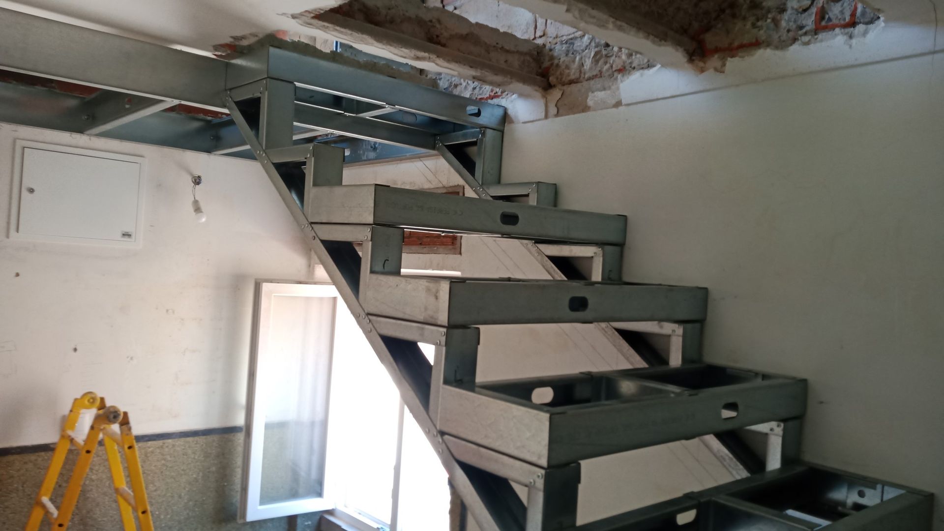 Estrutura metálica de escada em construção, com degraus e longarinas vazados.