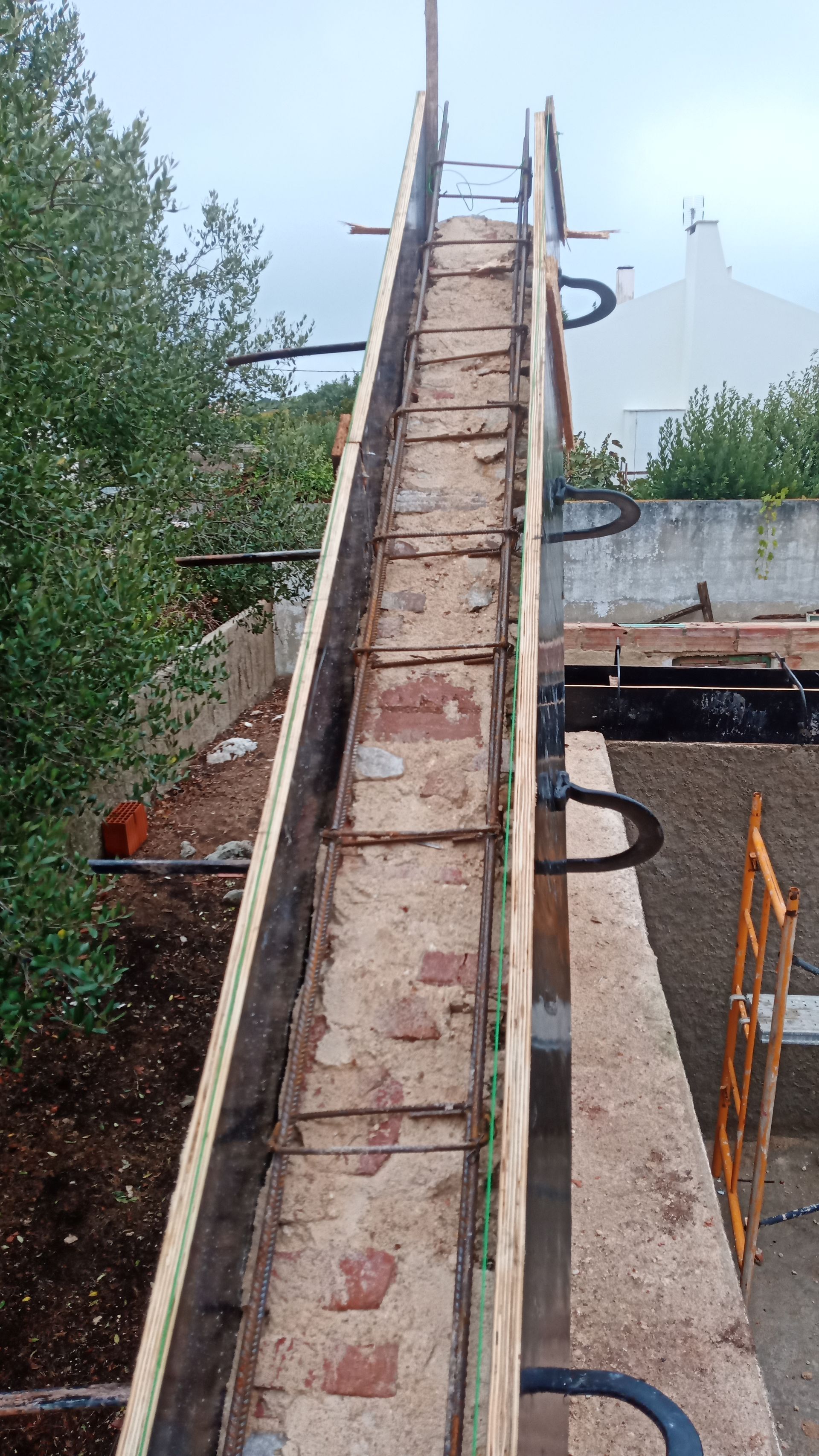 Calha longa e inclinada, construída em tijolo e madeira, possivelmente para transporte de materiais em um telhado.