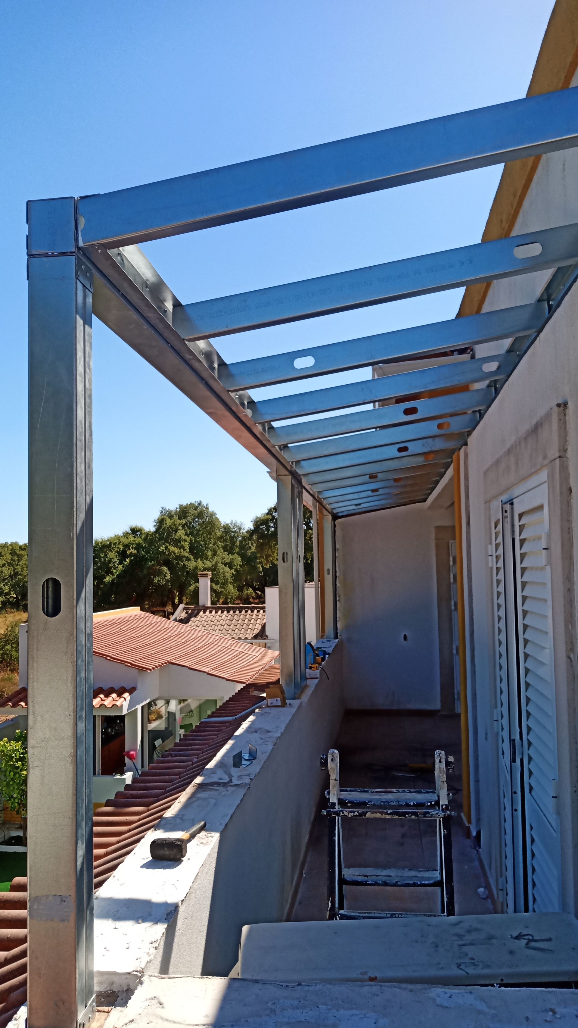 Estrutura metálica em uma varanda com um céu azul claro ao fundo.