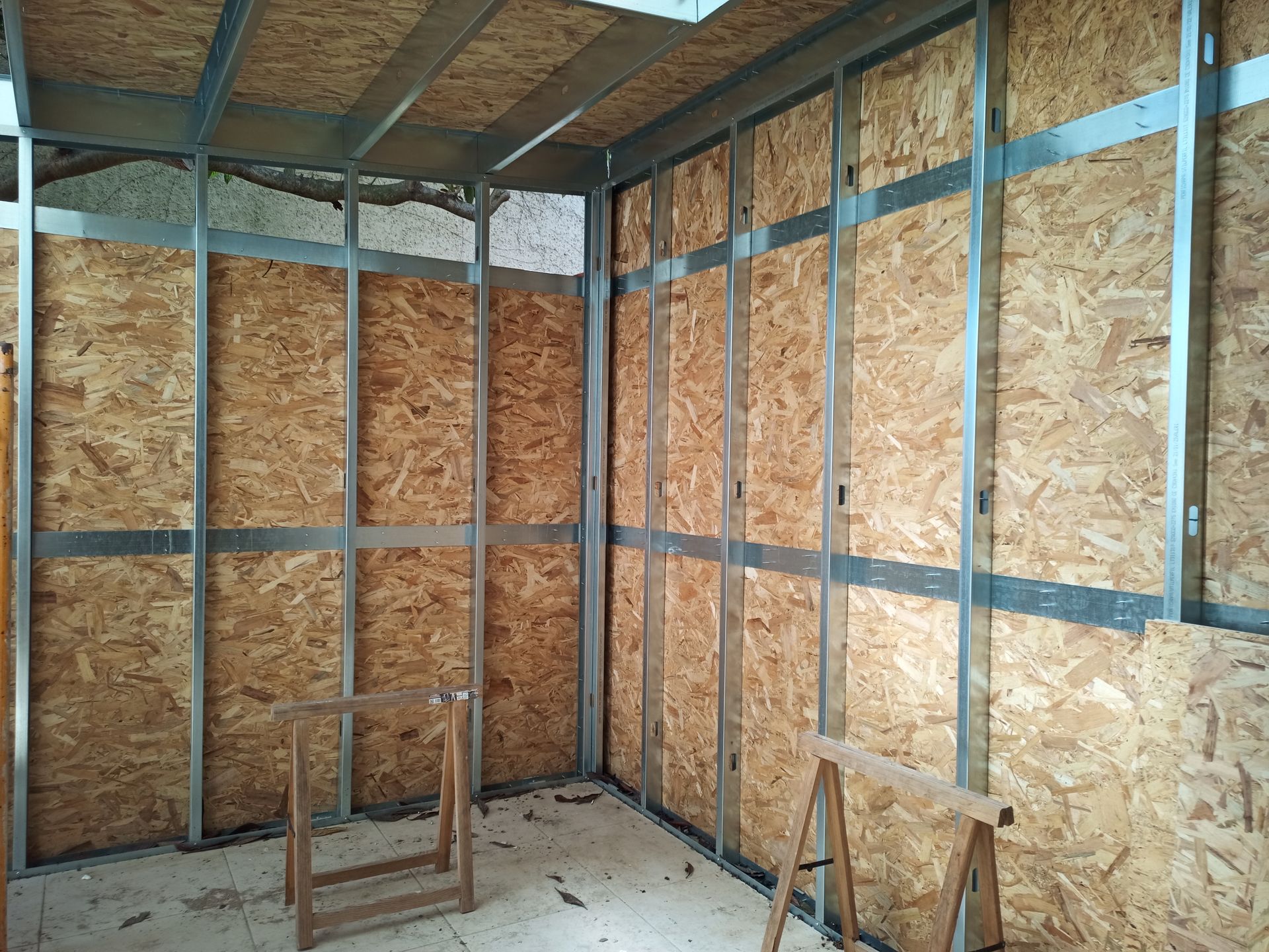 Estrutura interna de um cômodo com perfis metálicos e revestimento de OSB.