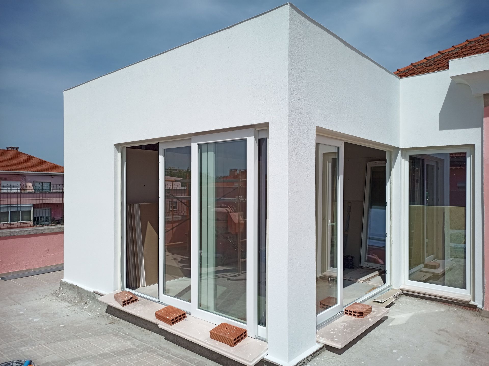 Estrutura no telhado com paredes brancas, portas de vidro deslizantes, janelas e detalhes em tijolo.