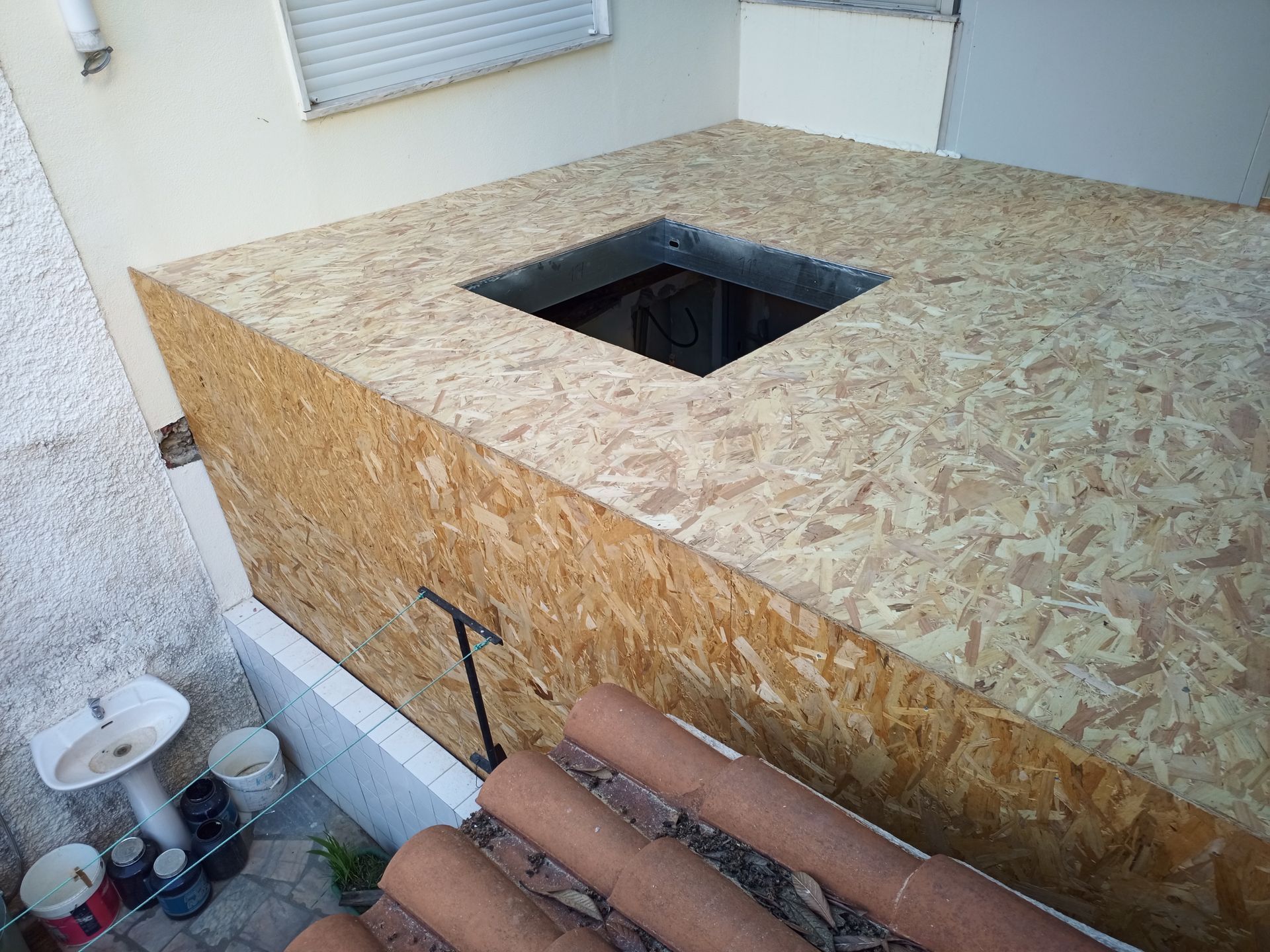 Uma estrutura de caixa de madeira com um buraco quadrado no topo, possivelmente um forno externo.