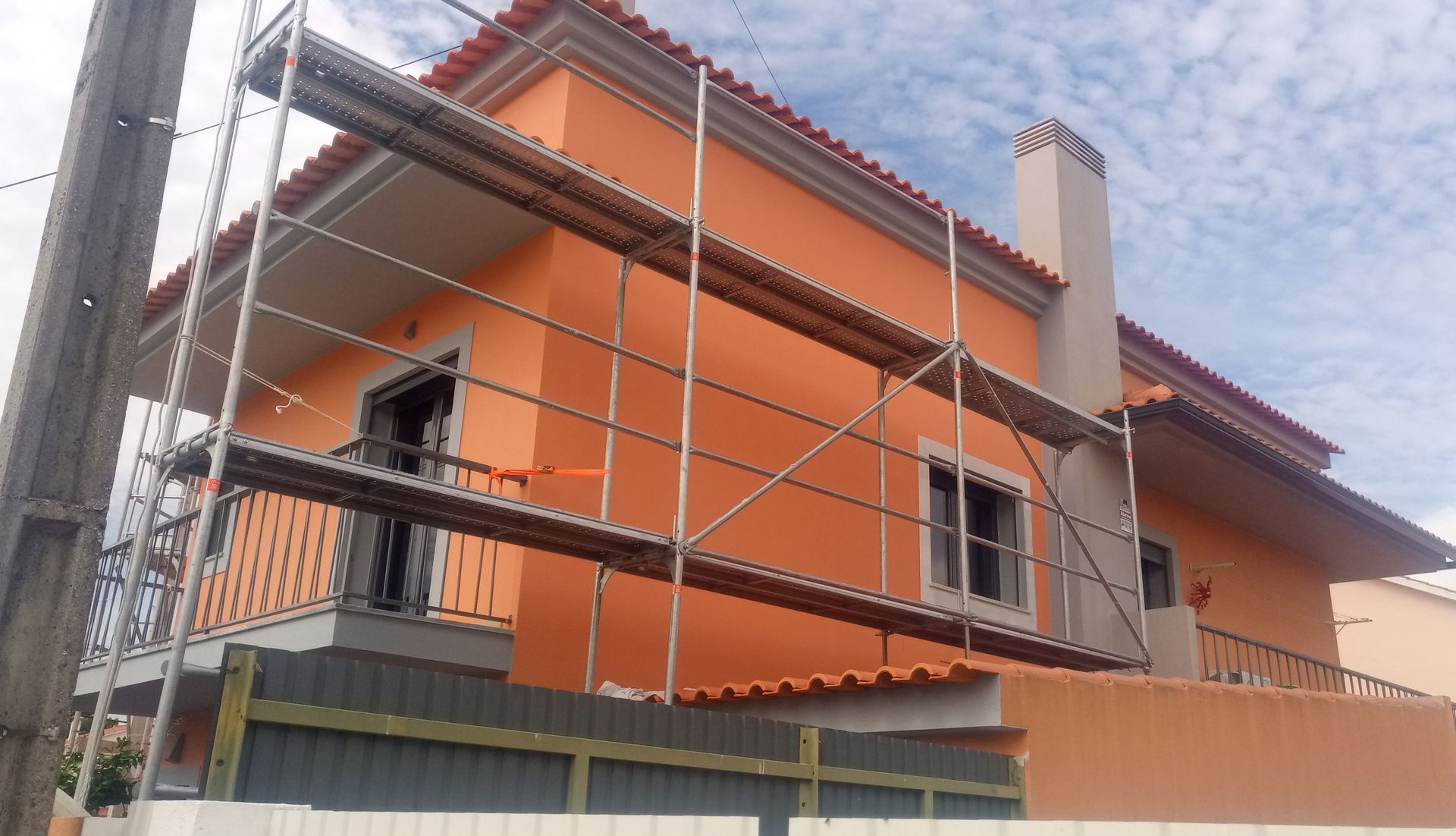 Casa laranja em construção com andaimes.