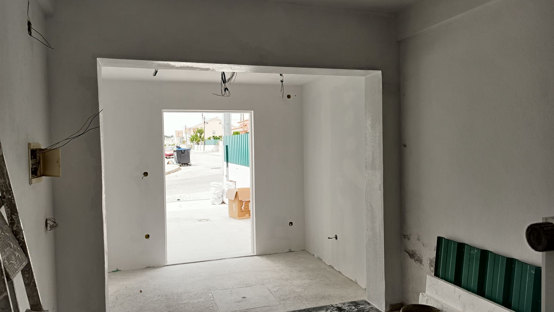 Quarto interior com paredes brancas recém-pintadas e uma porta aberta.