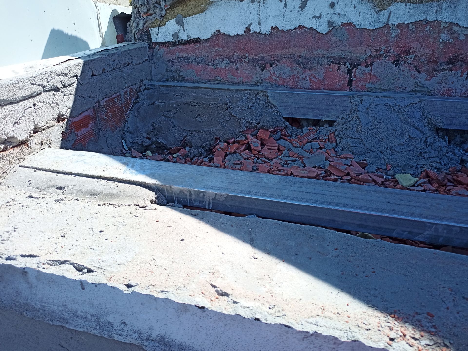 Estrutura de concreto danificada com tijolos expostos e entulho.