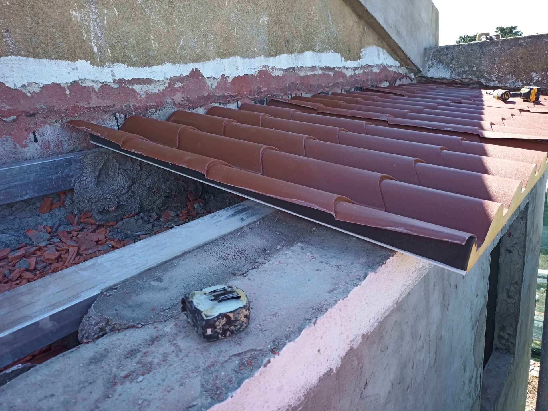 Telhas metálicas marrons sendo instaladas contra um edifício de concreto.