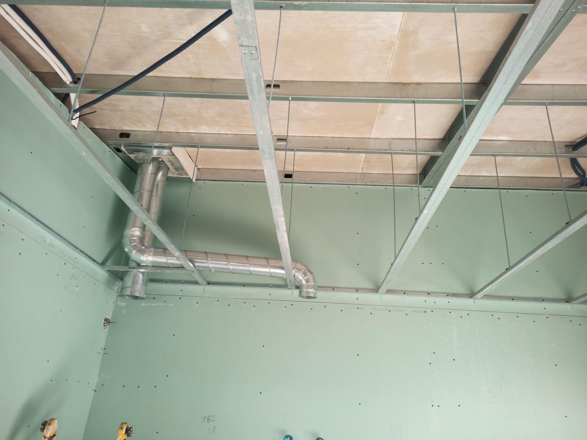 Teto e paredes em construção; dutos de ar instalados; drywall verde.