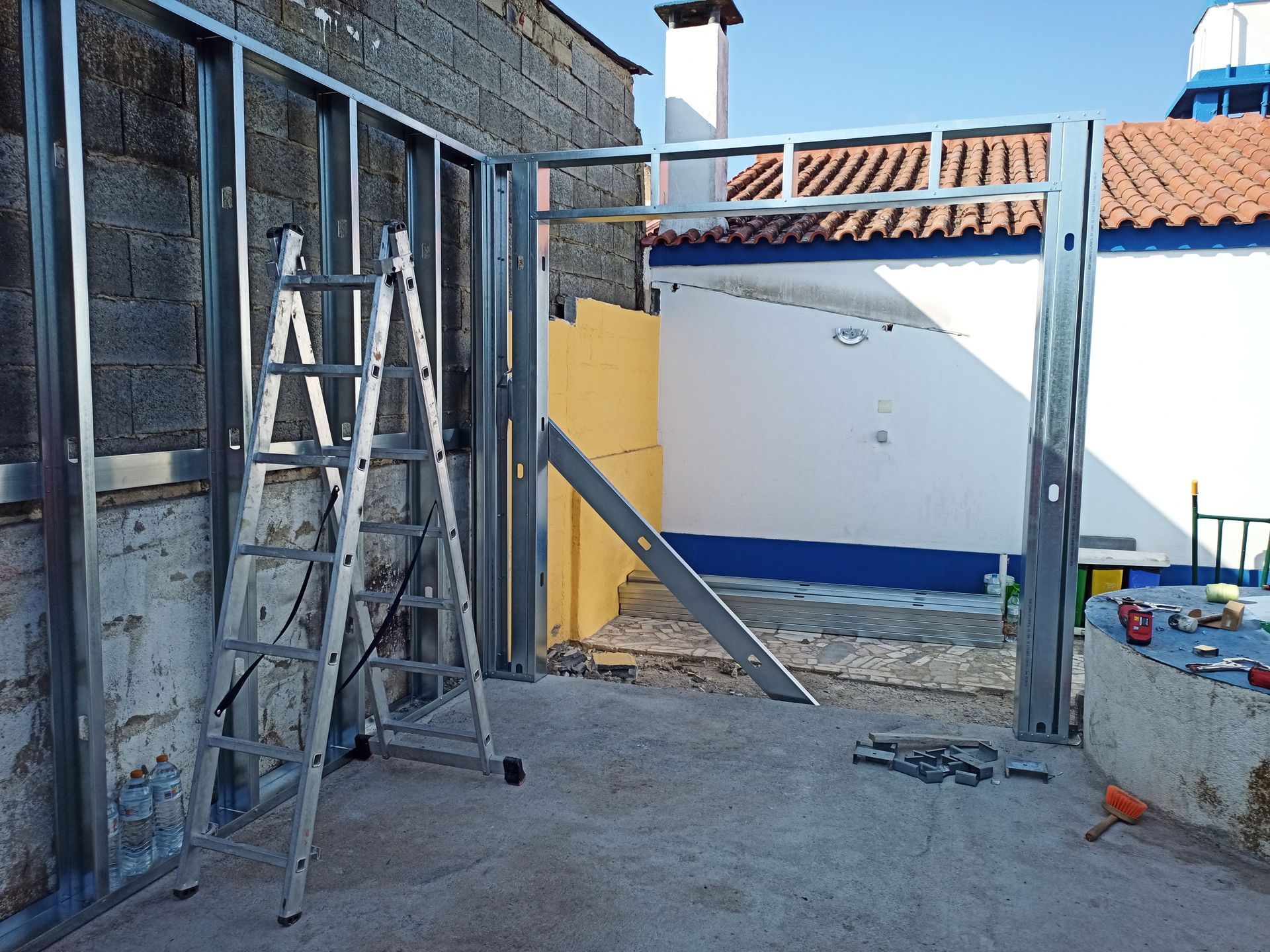 Estrutura metálica de suporte para uma construção; escada encostada na estrutura.