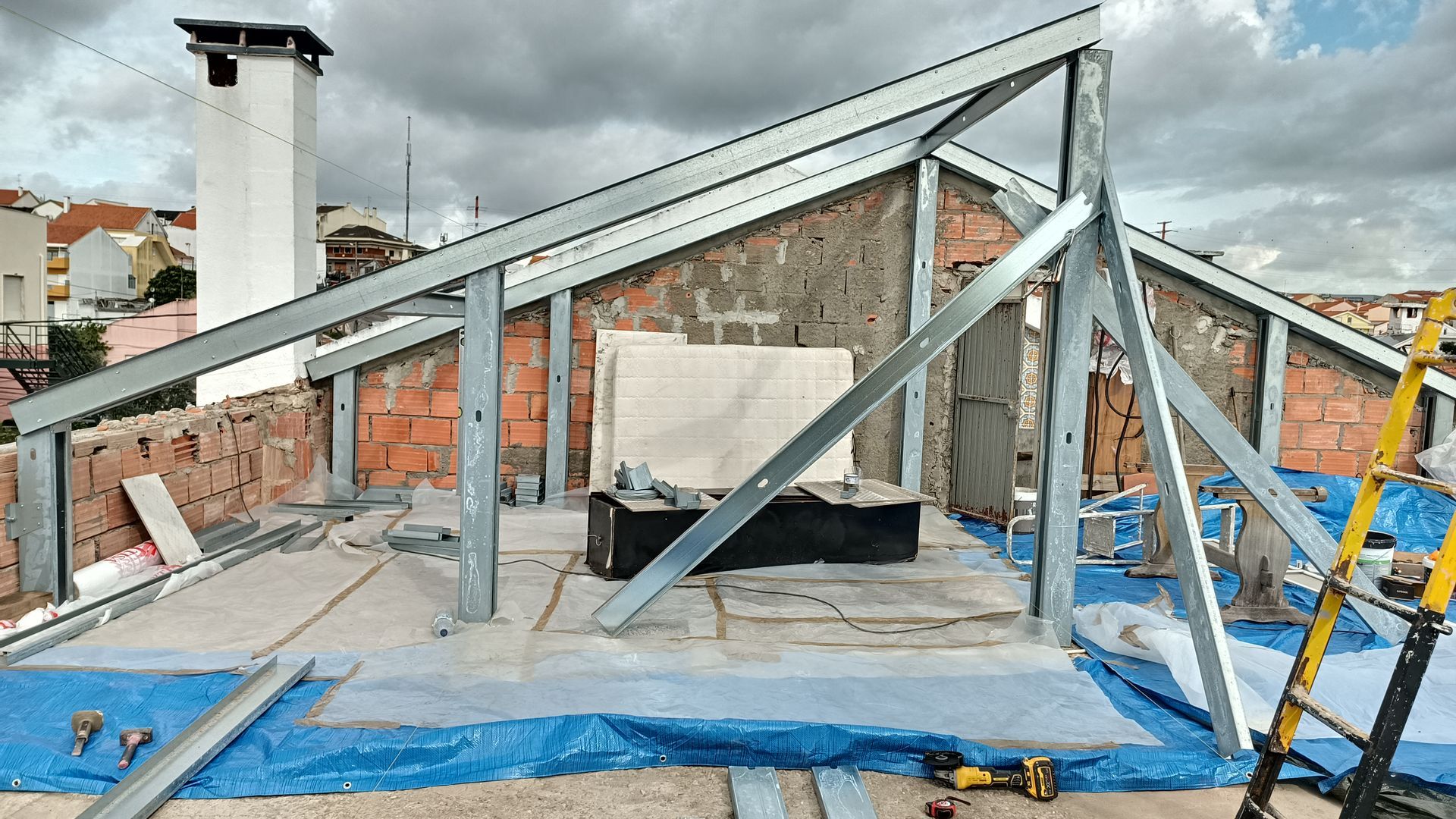 Construção com telhado de estrutura metálica em um prédio de tijolos sob um céu nublado.