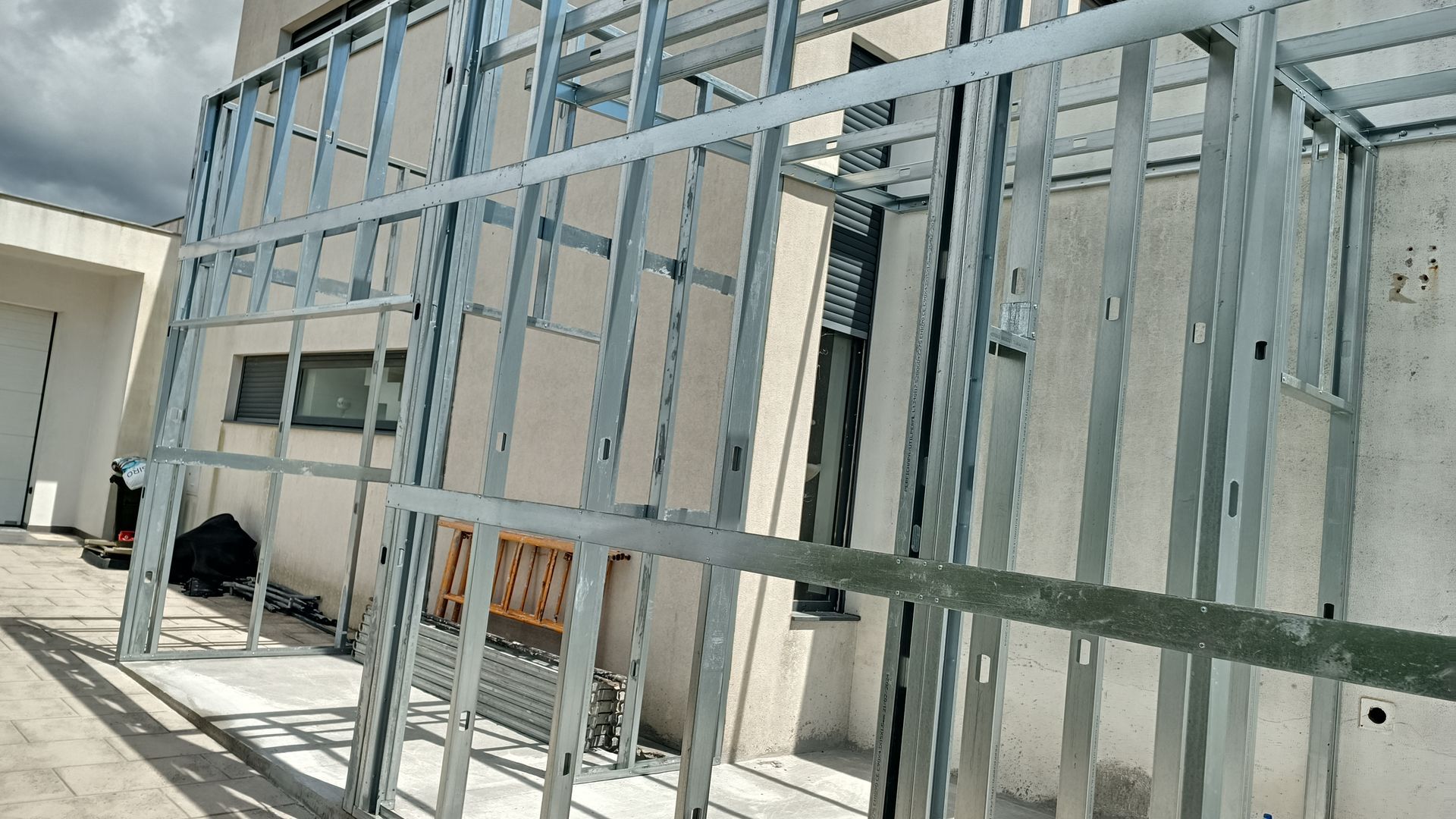 Estrutura metálica para paredes, encostada em um prédio ao ar livre em um dia ensolarado.