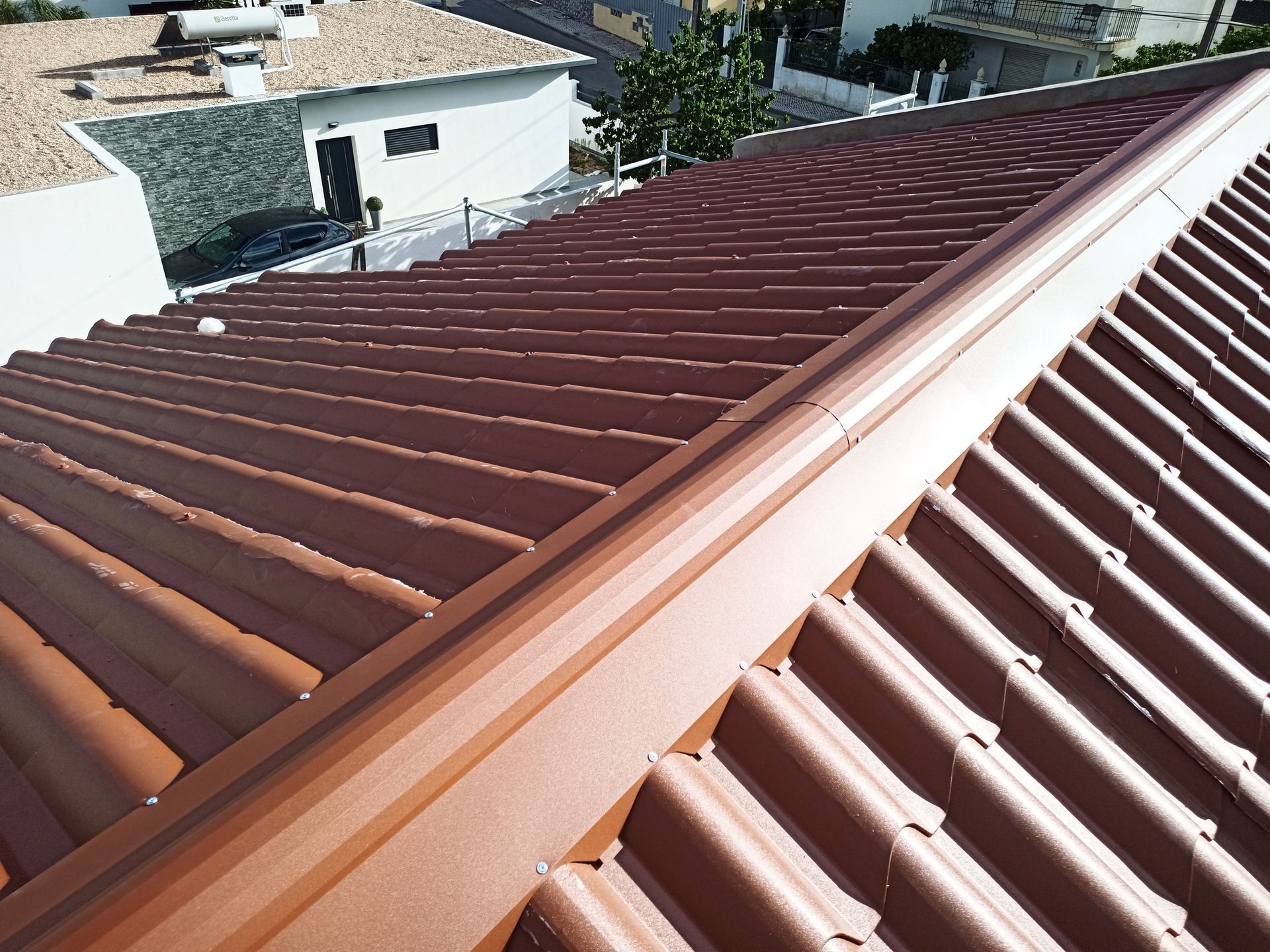 Telhado de metal marrom com cumeeira, visto de cima.