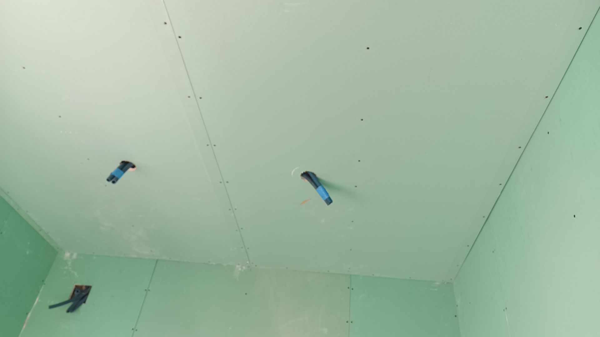 Teto e paredes de gesso cartonado verde com caixas elétricas; construção.