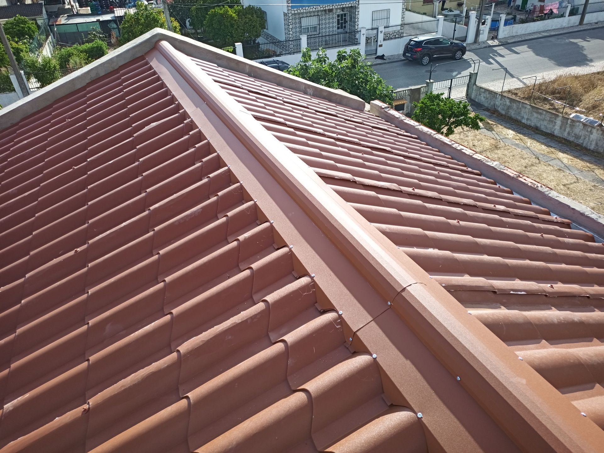 Telhas marrons com cumeeira combinando, vistas de cima, em um ambiente residencial.