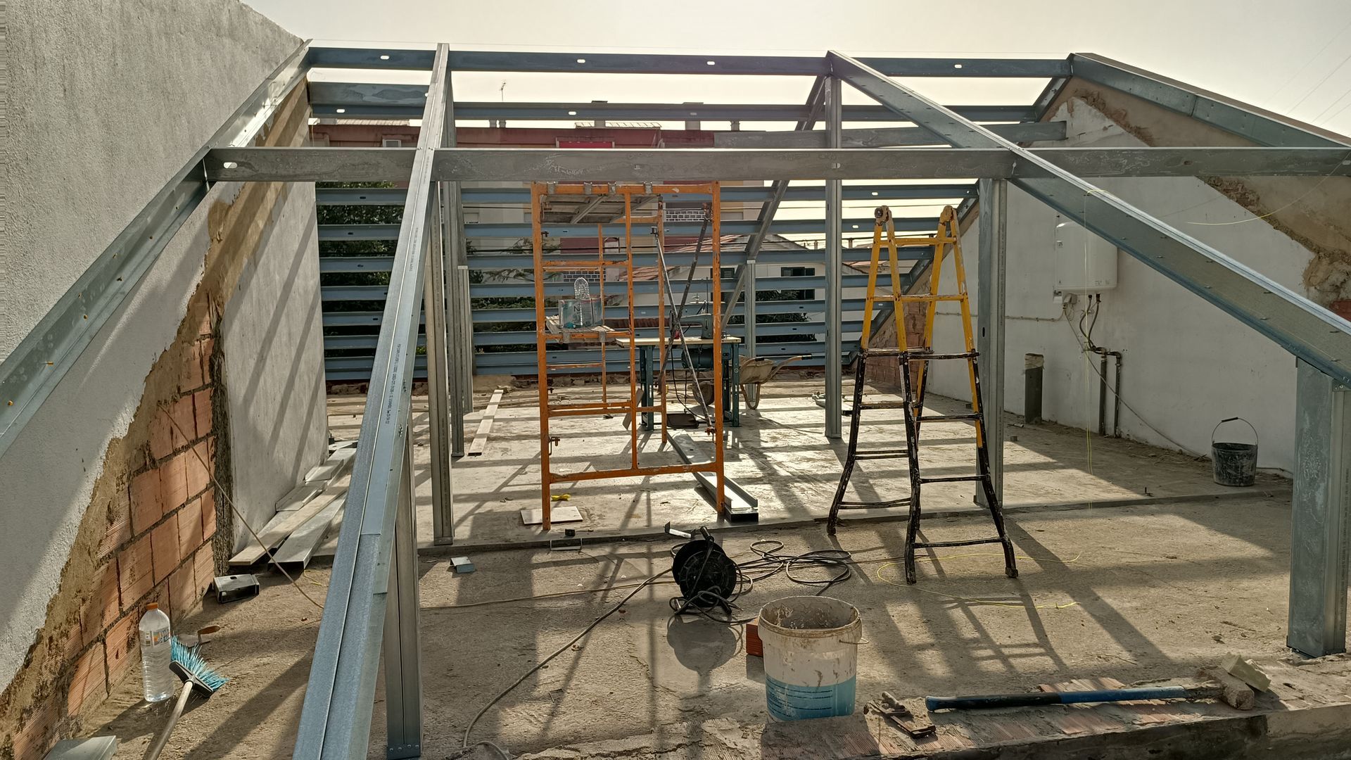 Construção interna com estrutura de aço e andaimes; obra em andamento.