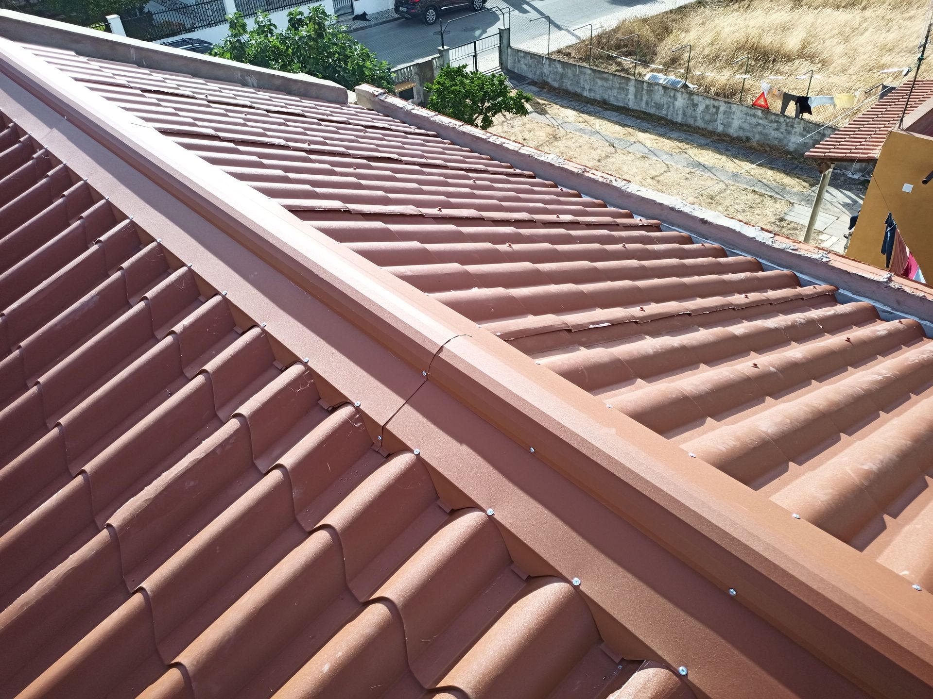 Telhado de telha marrom com calha marrom instalada ao longo da beirada do telhado.