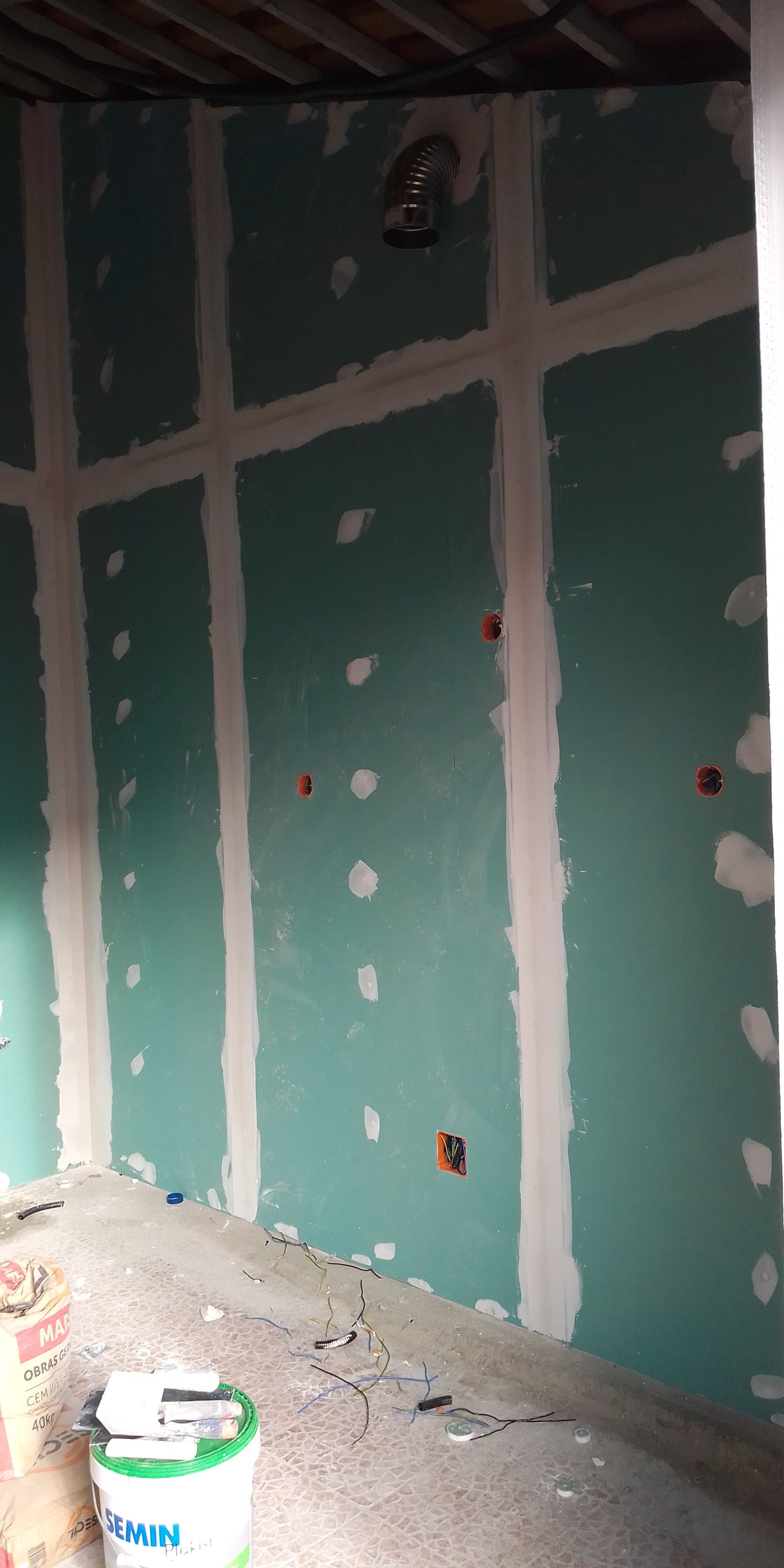 Quarto interior com parede de gesso acartonado, tomadas elétricas e um balde.