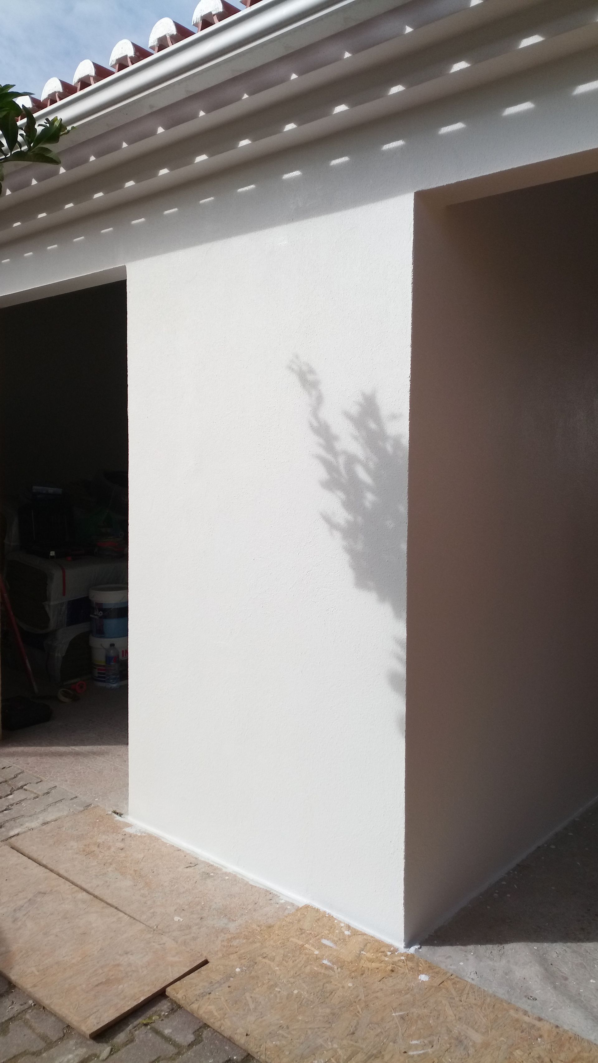 Parede de estuque branco com porta e sombra.