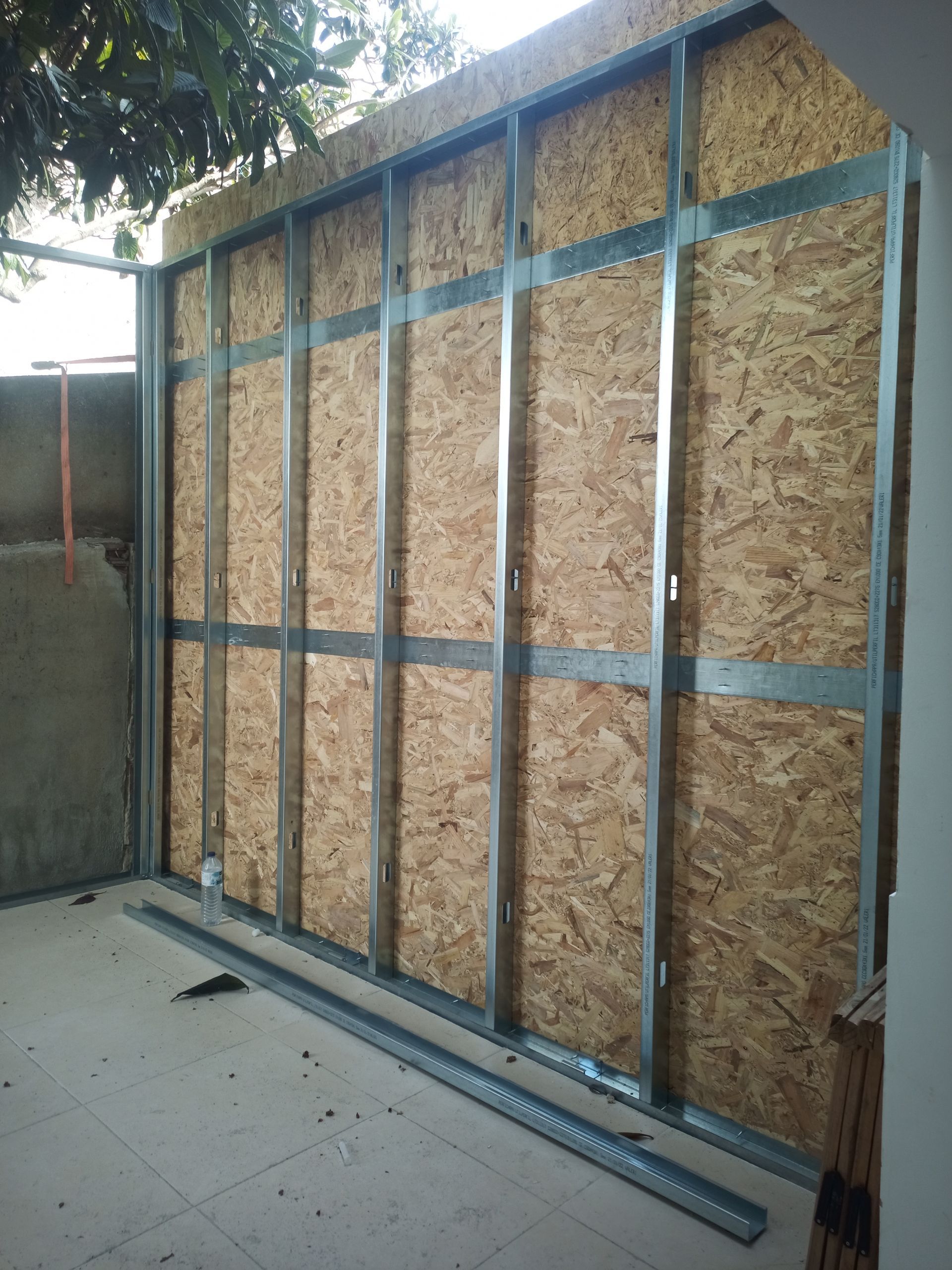 Parede com estrutura metálica e painéis de madeira. Canteiro de obras.