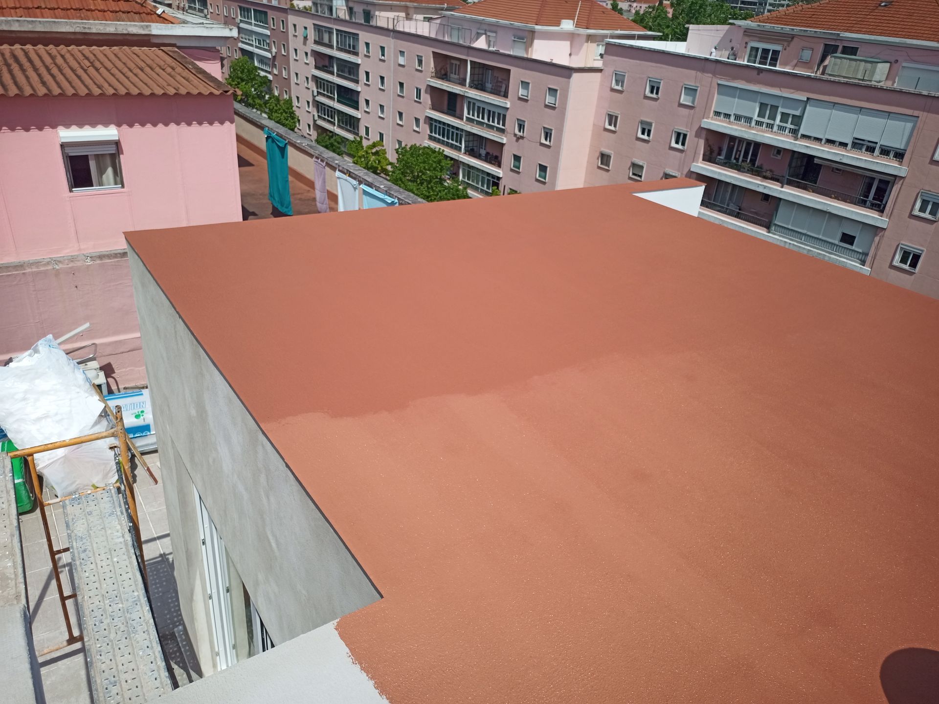 Um terraço plano pintado de marrom-avermelhado em um ambiente urbano com prédios de apartamentos.