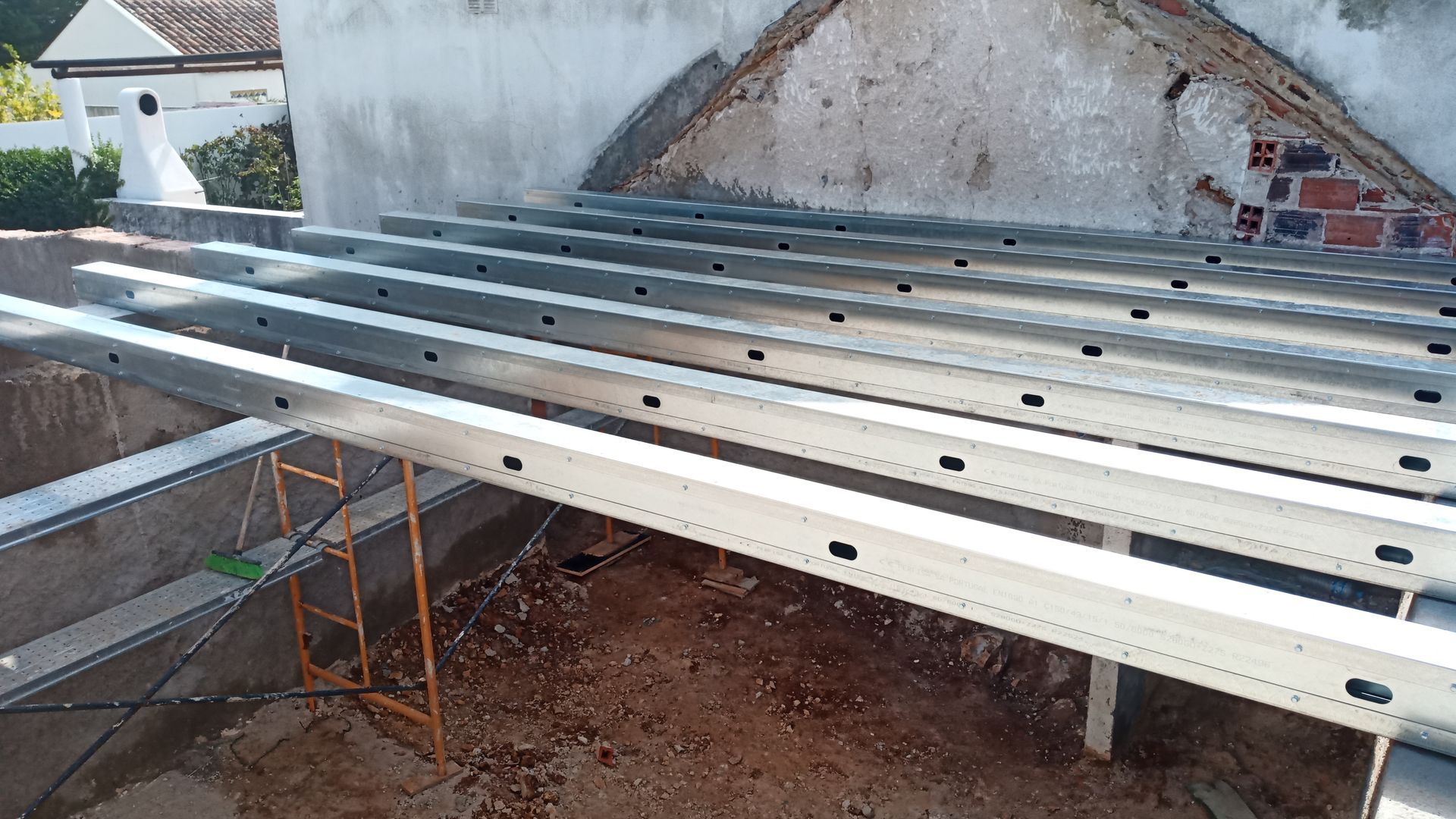 Vigas metálicas instaladas em um telhado, possivelmente para montagem de painéis solares. Construção em andamento.