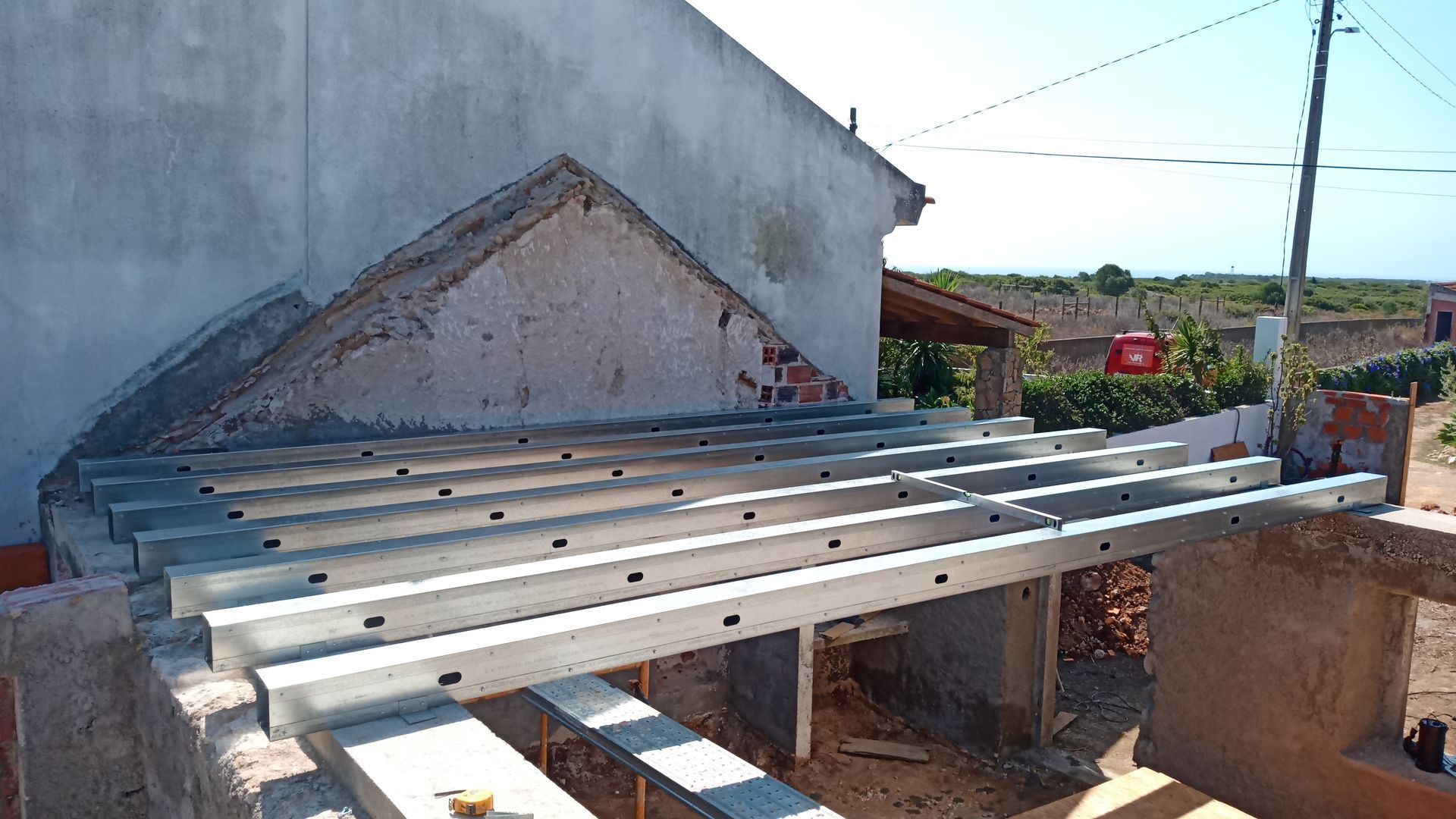 Construção de uma cobertura com estrutura de vigas metálicas em um edifício. Dia nublado.