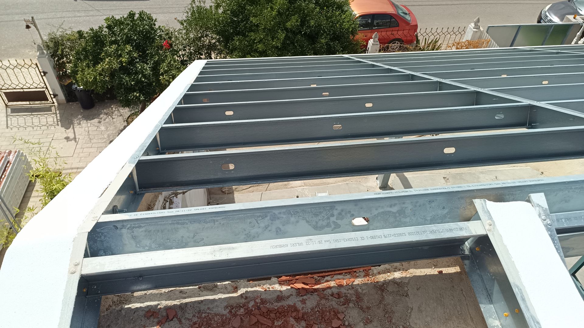 Estrutura metálica do telhado de um edifício, construída com vigas, em um ambiente com luz natural.