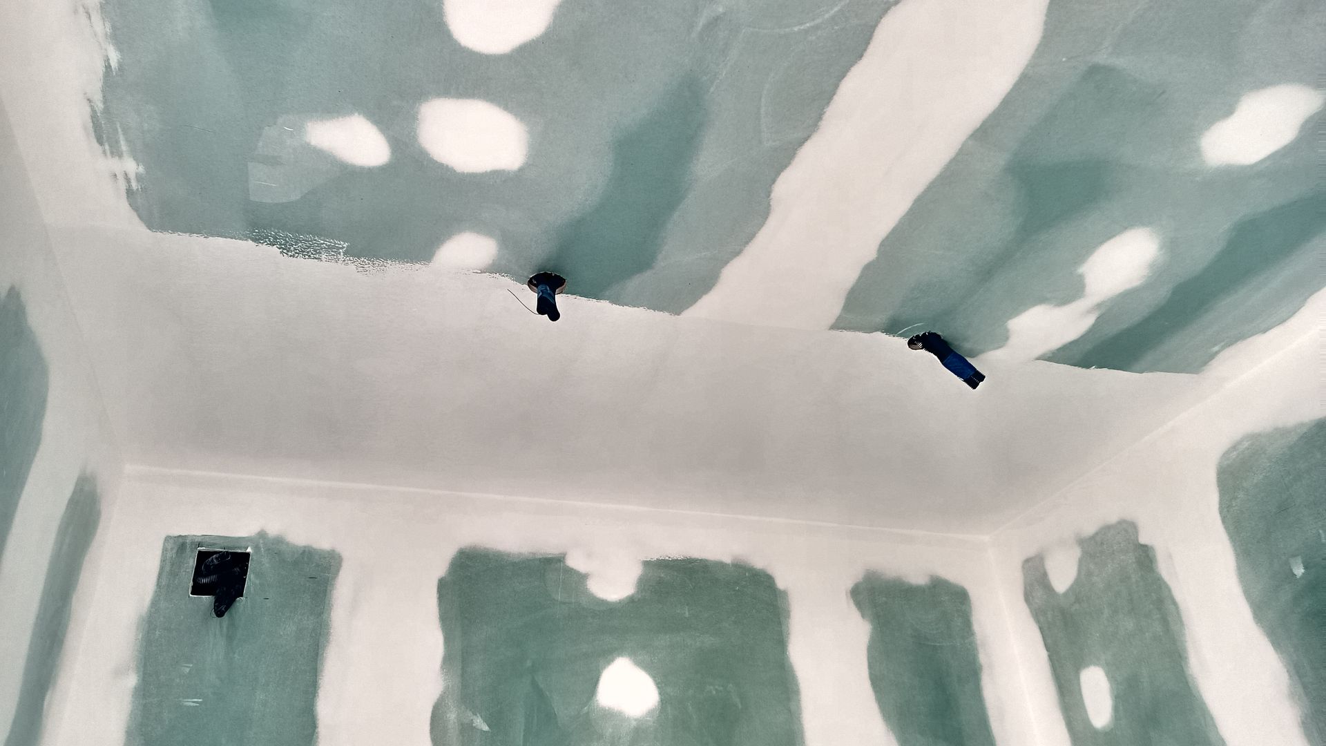 Interior de um cômodo com paredes e teto de gesso acartonado, parcialmente revestidos com massa corrida branca.