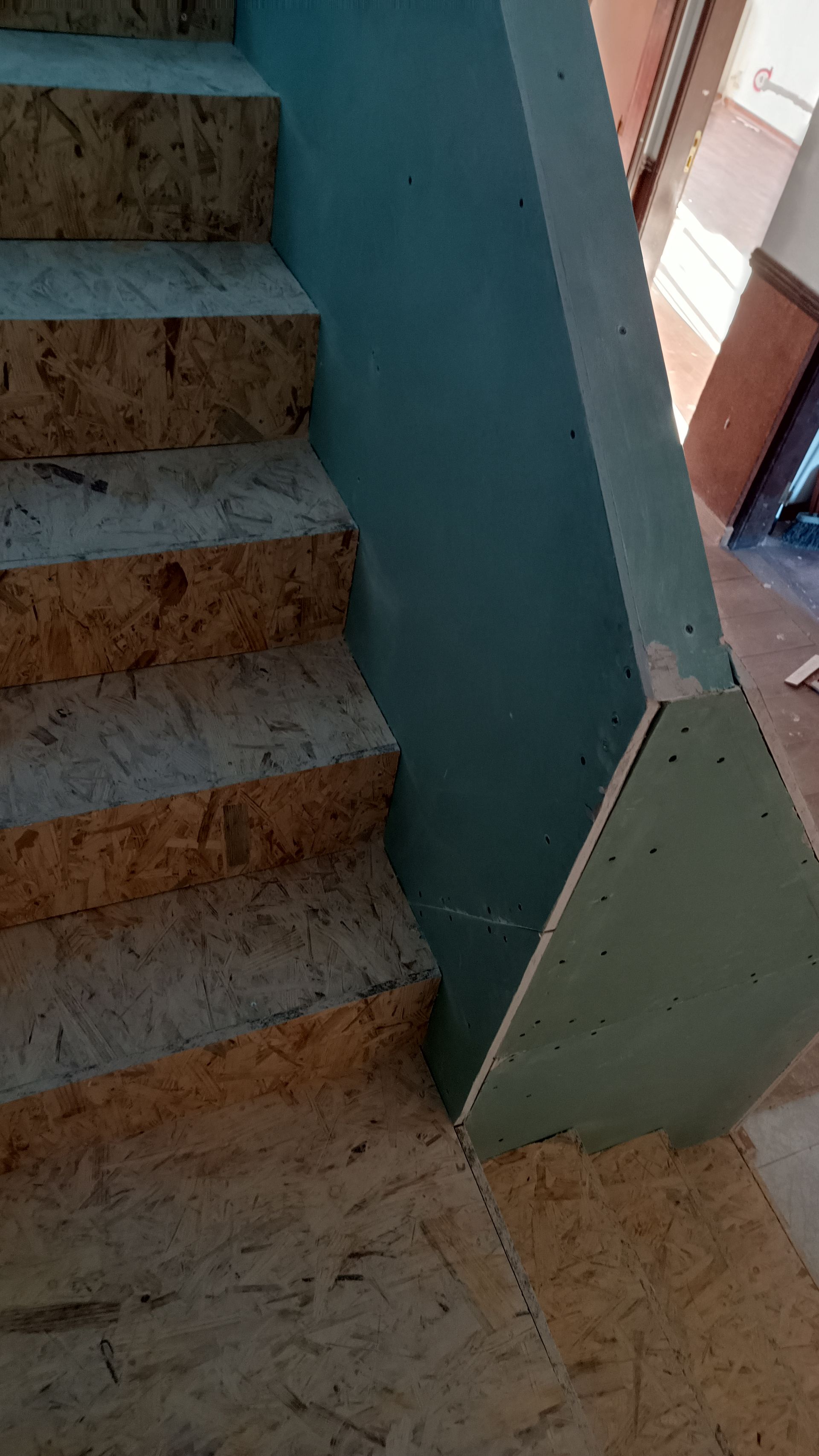 Escada de madeira com painéis laterais de gesso cartonado azul.