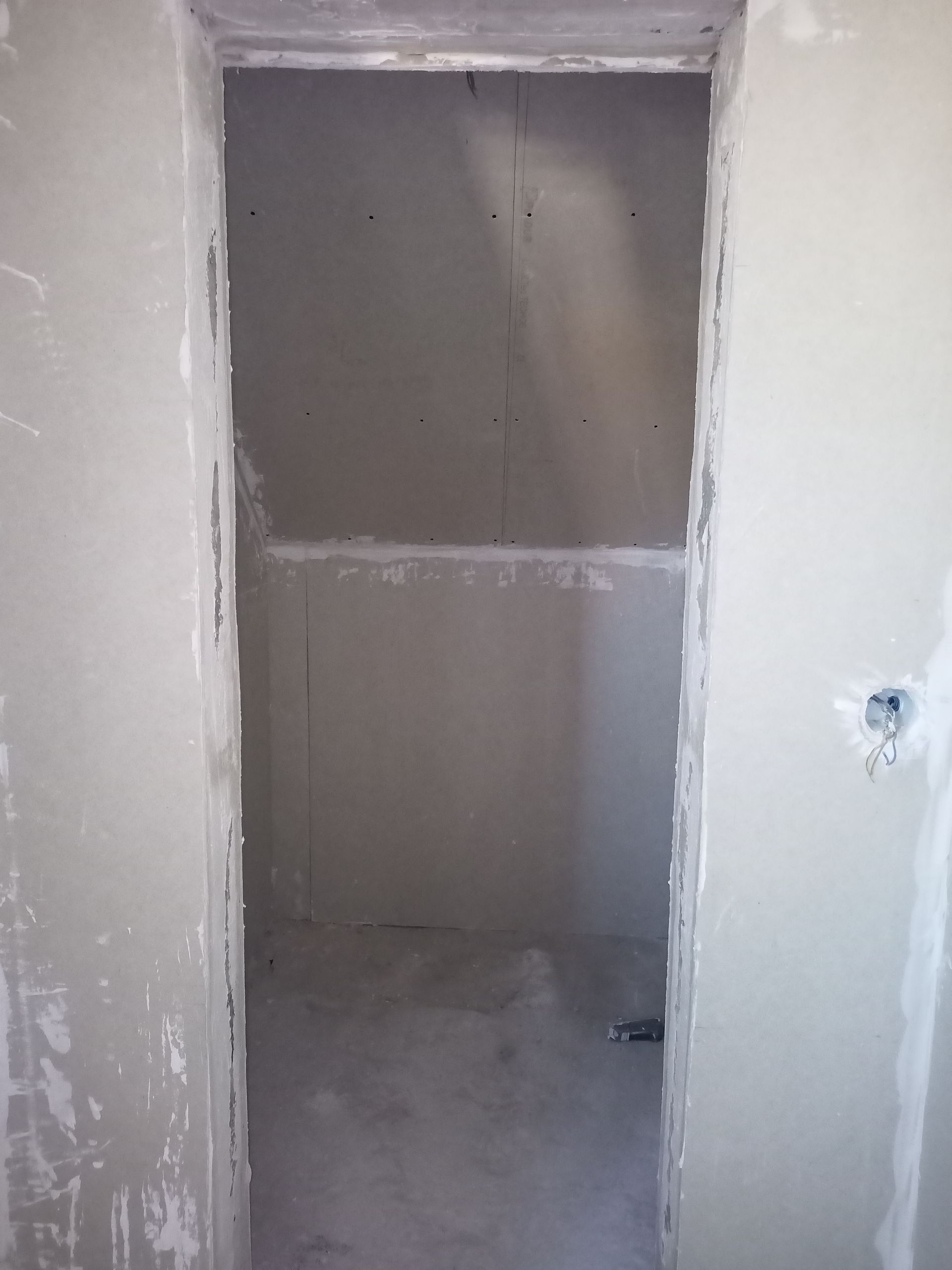 Porta interna, parede de gesso inacabada.