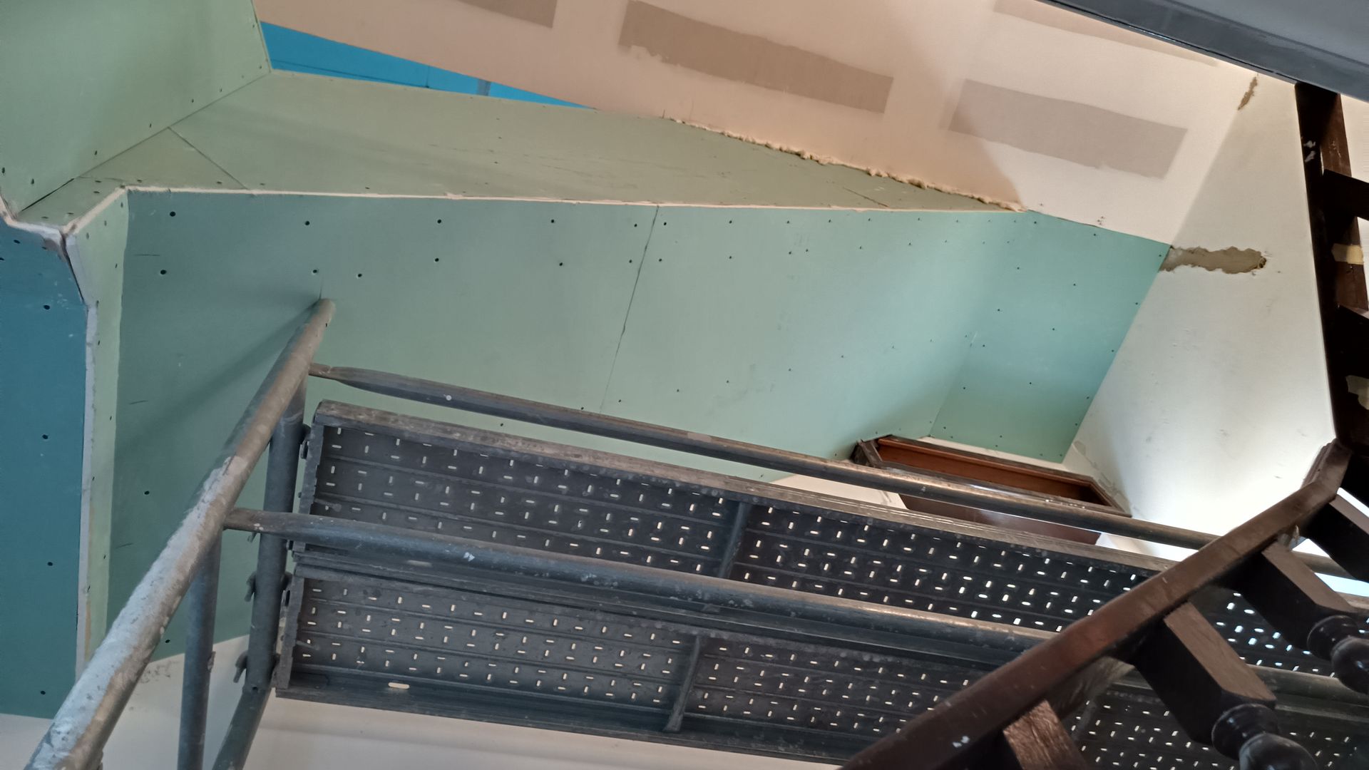 Construção de escada: instalação de drywall no teto com andaimes e escada.