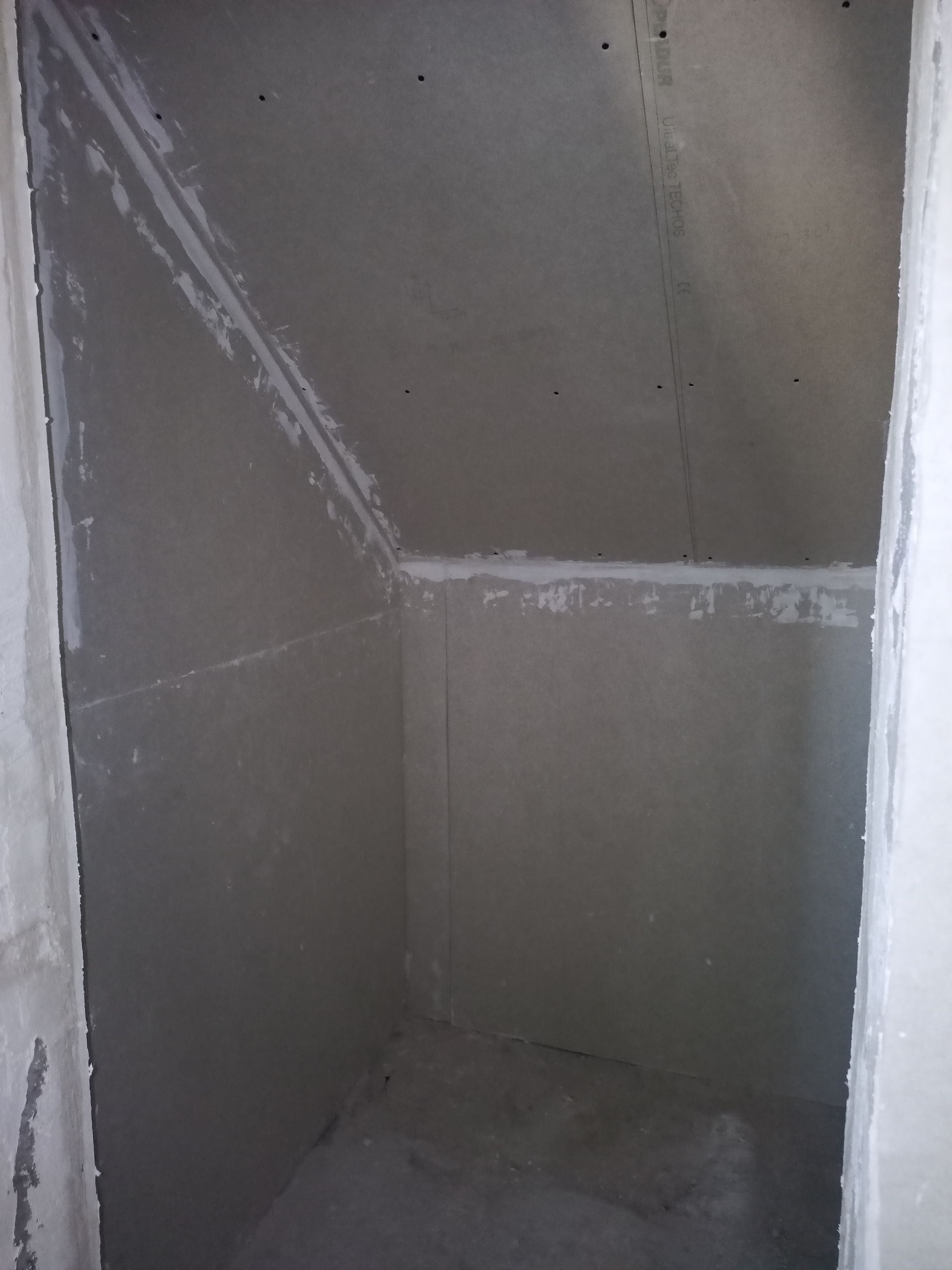 Closet vazio e inacabado com paredes de gesso acartonado e teto inclinado.