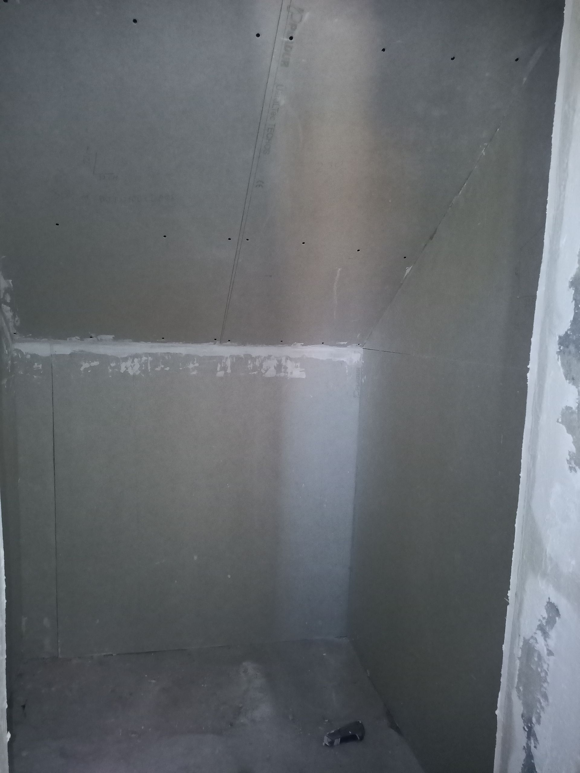 Sala vazia com paredes cinzentas e piso de concreto, pronta para acabamento.