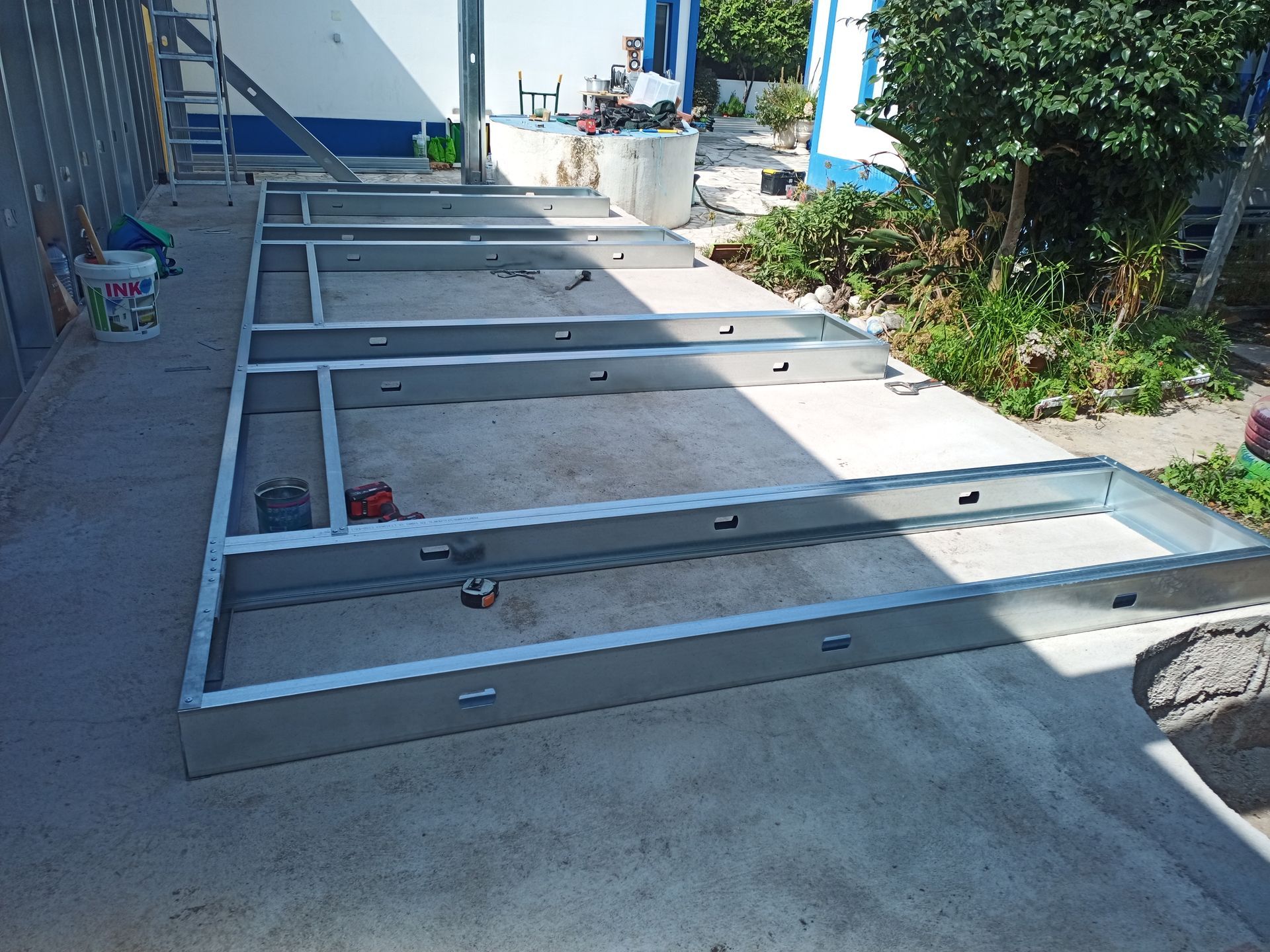 Estrutura metálica para a fundação de um edifício sobre uma laje de concreto, em área externa.