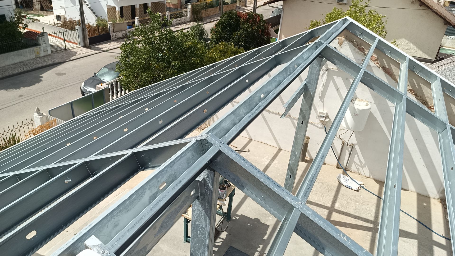 Construção da estrutura metálica do telhado em andamento, vista de cima.