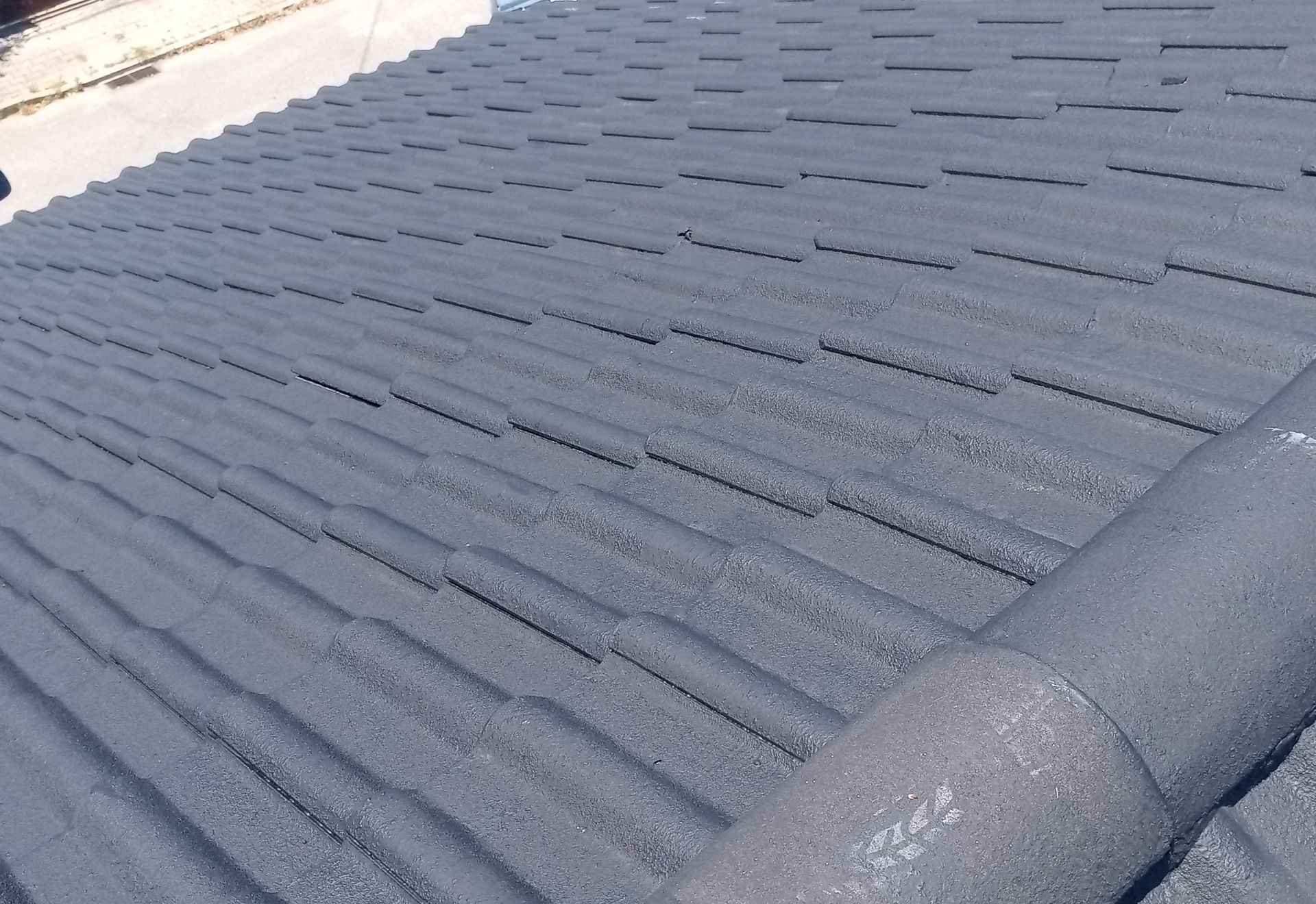 Telhado de telhas cinzentas num dia ensolarado.