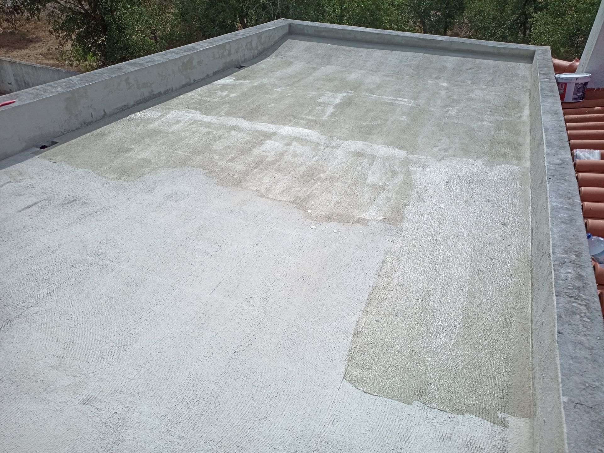 Telhado de concreto com textura visível e manchas claras; as bordas são delimitadas e a área inclui telhas.