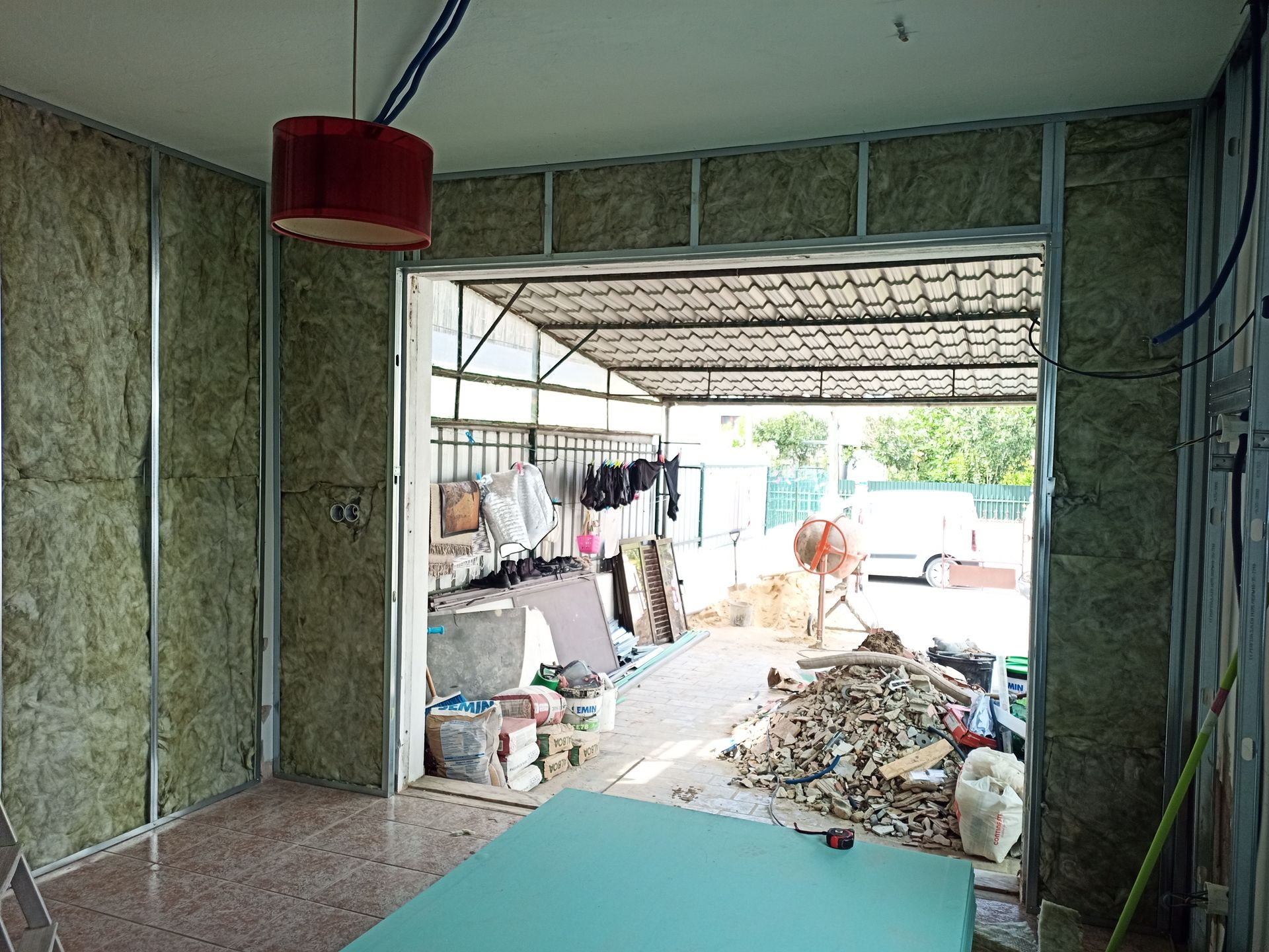Sala em construção, com estrutura de aço e isolamento. A porta aberta dá acesso à área de trabalho externa.