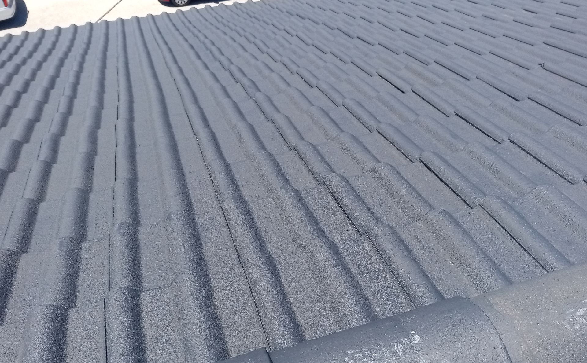 Telhado de metal ondulado cinza, visto de um ângulo em um dia ensolarado.