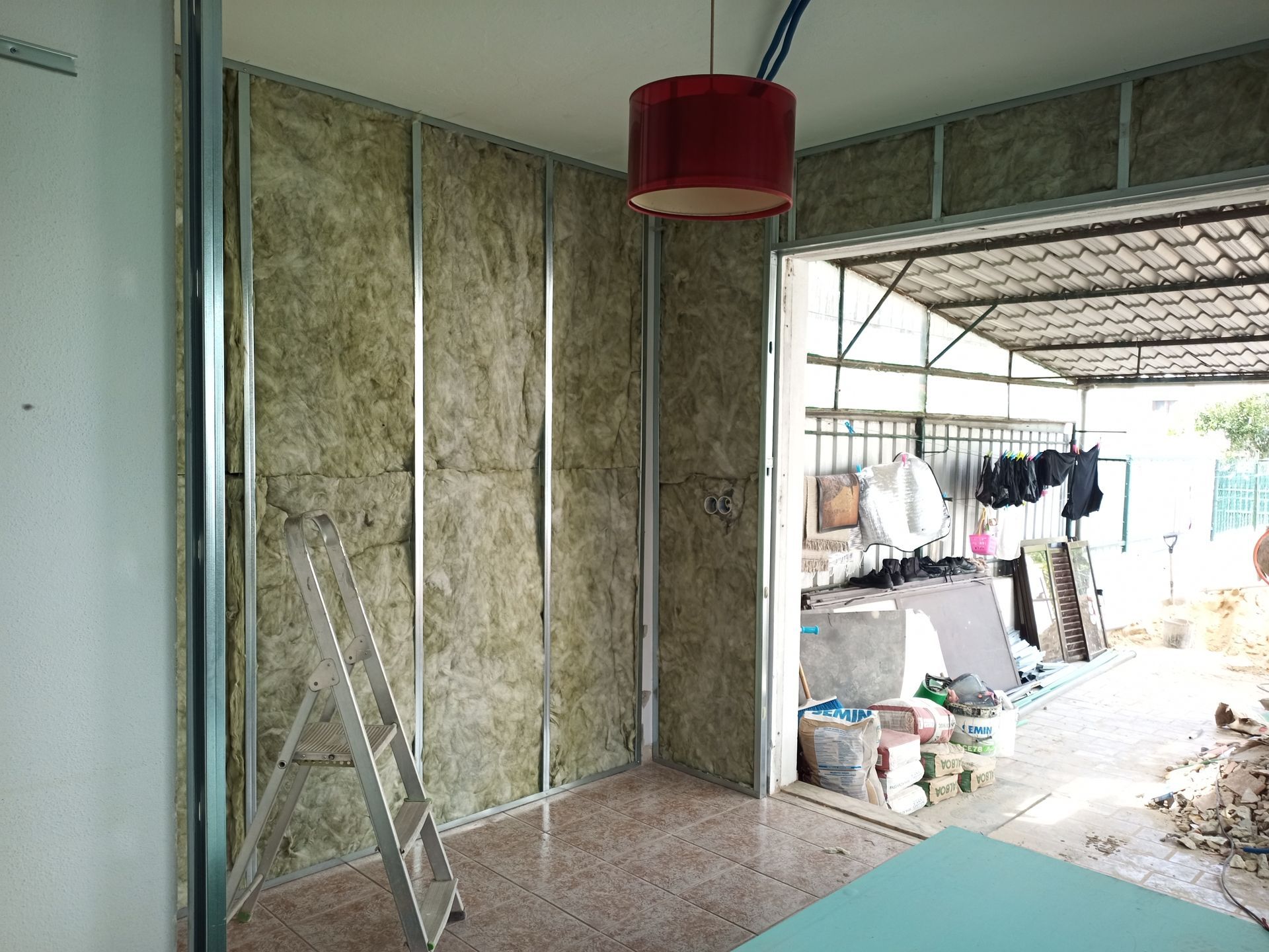 Reforma interna com isolamento entre perfis metálicos. Uma escada está próxima.