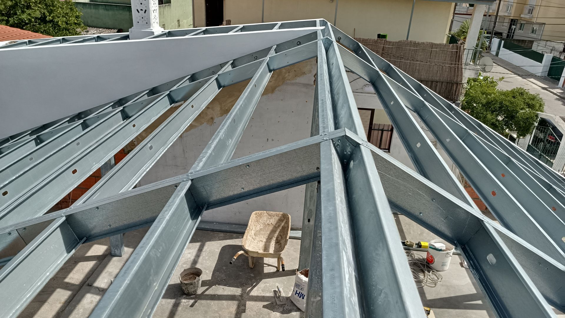 Estrutura de telhado de aço em construção com vigas metálicas cinzentas.