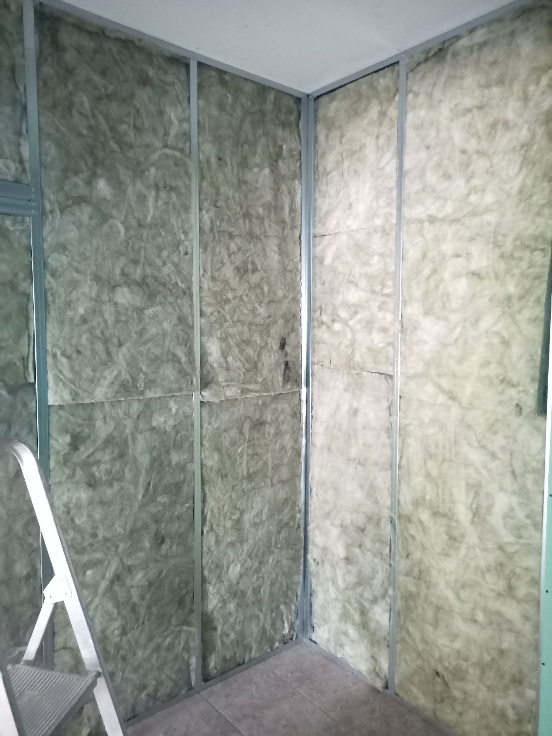 Construção de parede interna com perfis metálicos e isolamento instalado.